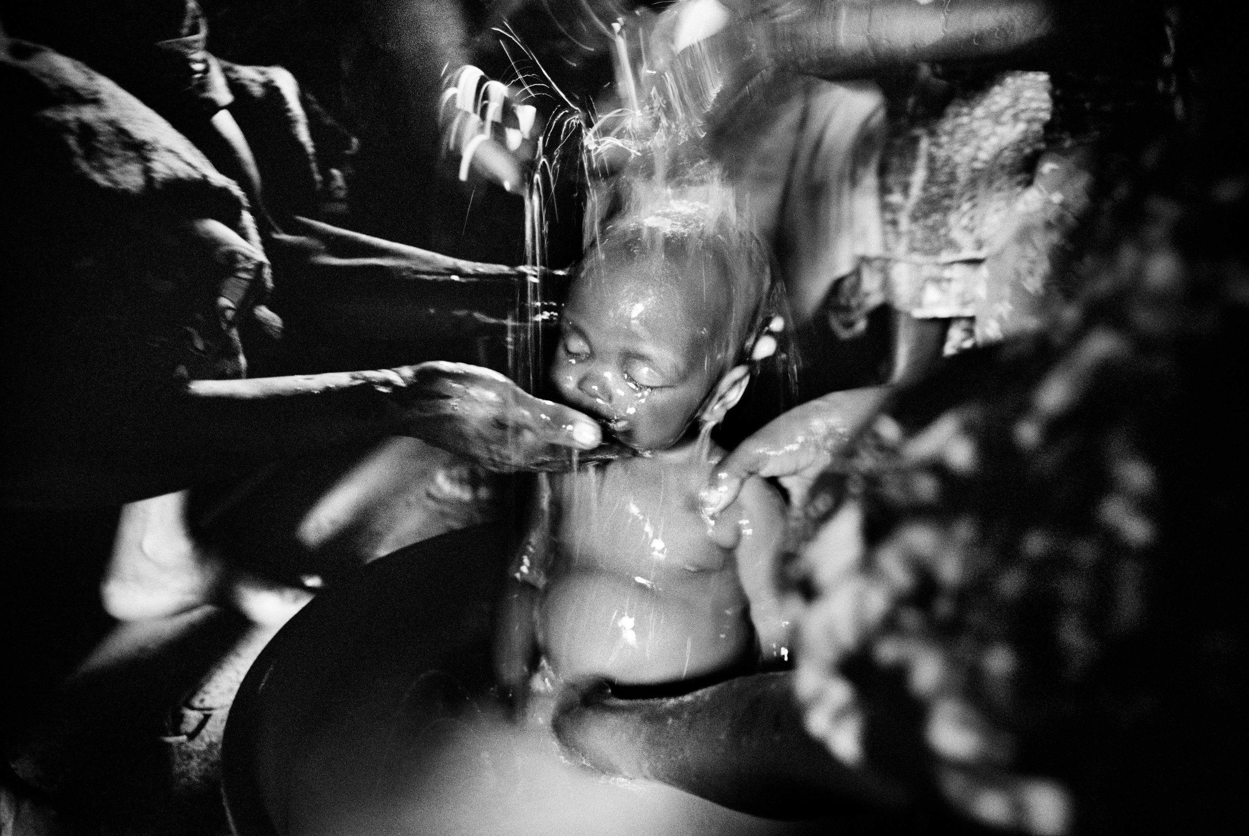 The washing of the body at the burial of the eight-month-old Sakura Lisi, the daughter of a gold miner in Mongbwalu, northeastern Congo. 2004