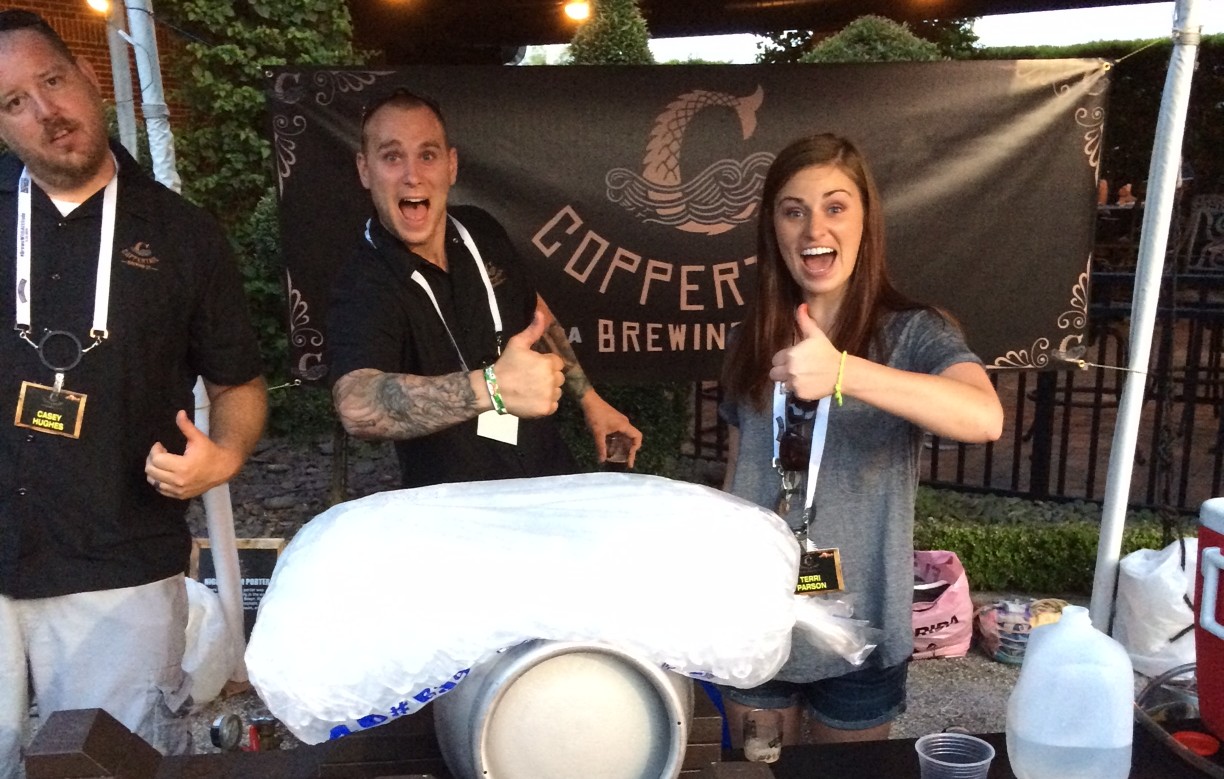 Assistant Brewer, Derrick Gough, and his wife, Erin Gough, serve up beer at a local beer fest while some weird guy crowds into the picture (on the left.)