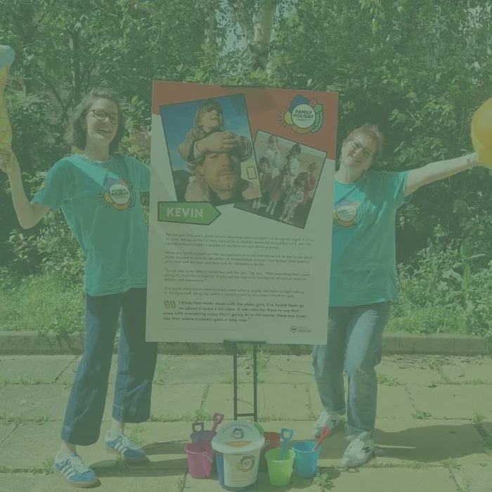 Two people holding inflatable holiday equipment in front of a charity stand