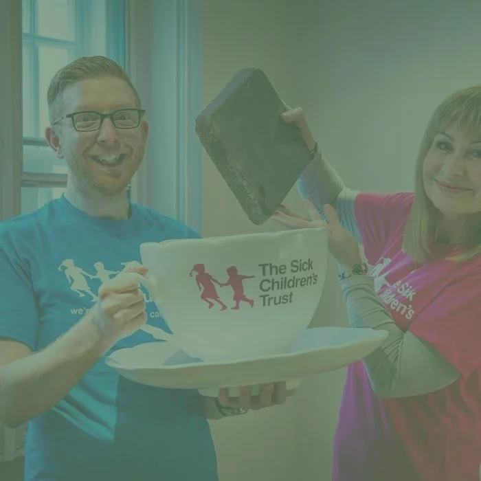 Paul A Young and Sian Lloyd dipping a large piece of chocolate into a giant tea cup