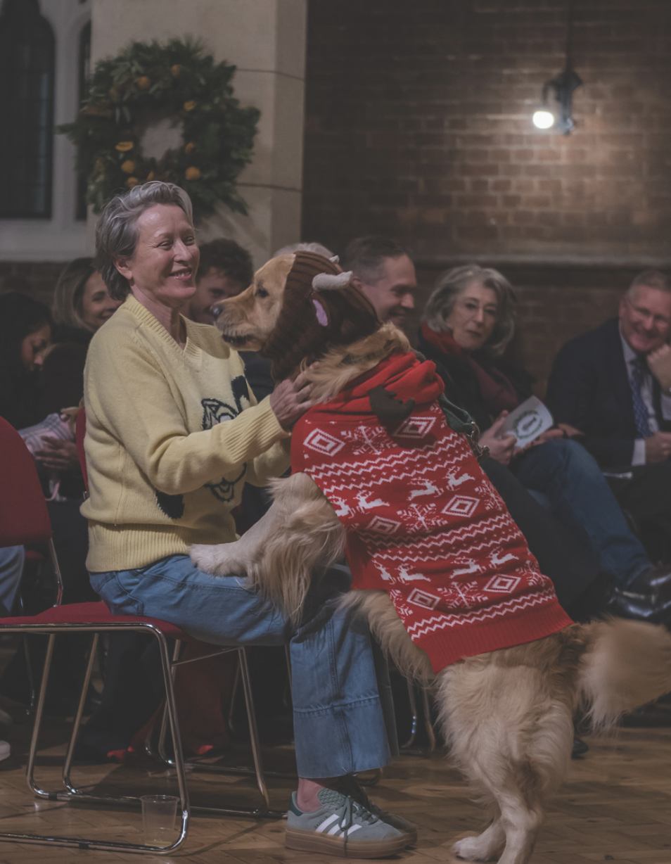 Woman holding a dog at a Christmas carol concert