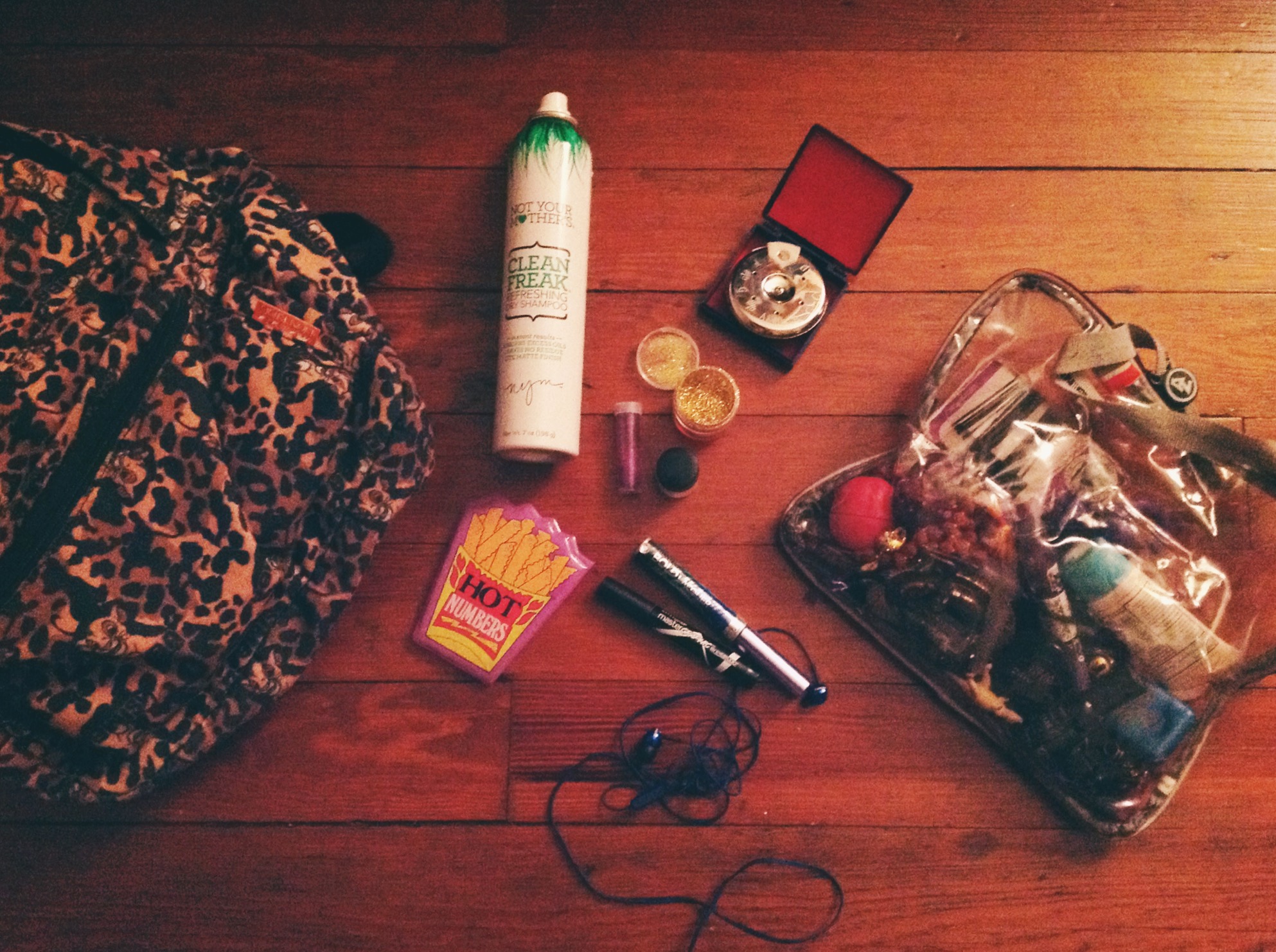 Clockwise from left: Simba backpack, Not Your Mother's Dry Shampoo, glitters, Johnson Chromatic Pitch Pipes, makeup pouch, earbuds, Maybelline Master Graphic by Eyestudio liquid eyeliner, R evlon Bold Lacquer Waterproof Mascara by Grow Luscious , "Hot Numbers" notepad.