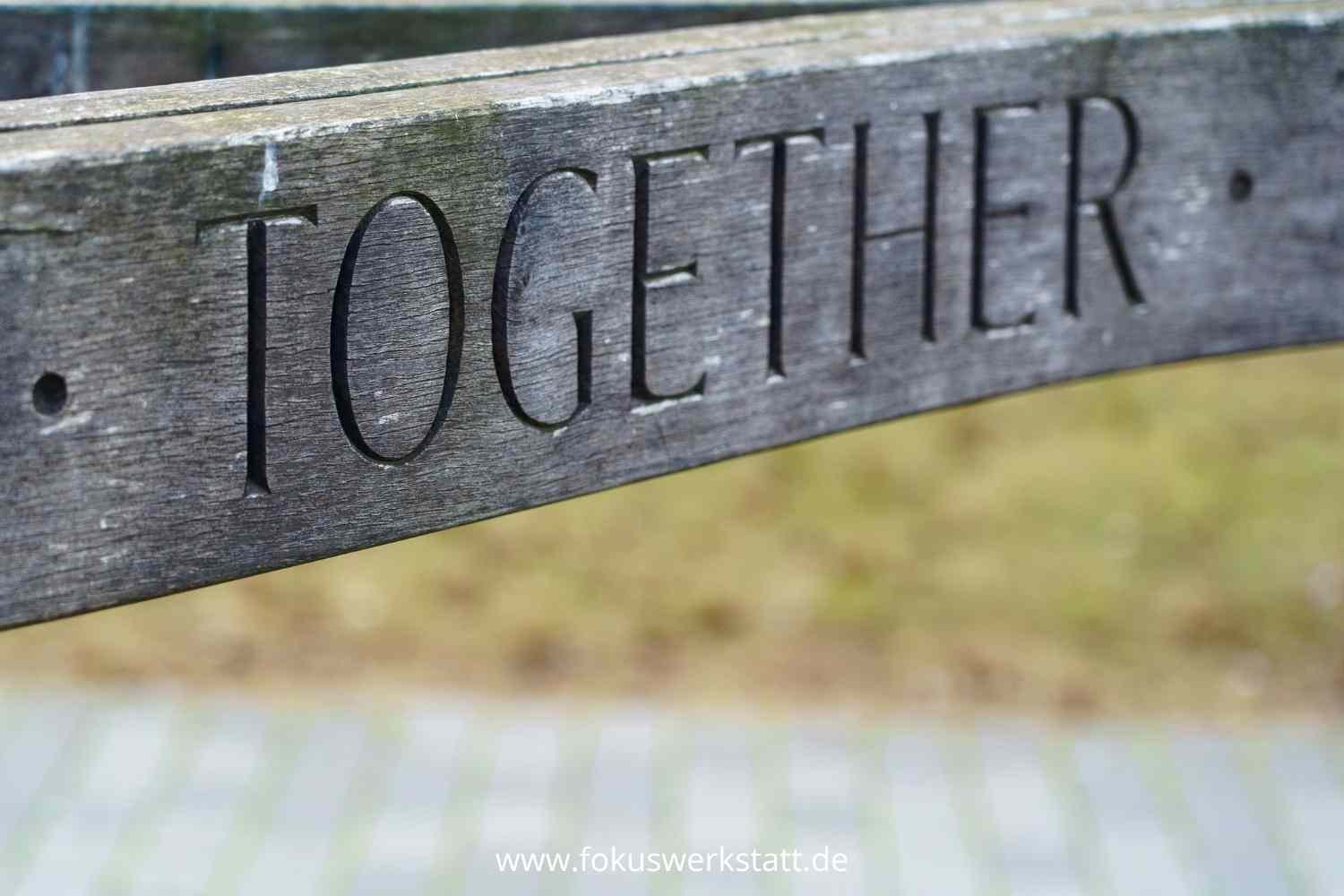 Das Bild zeigt ein Holzschild auf dem TOGETHER eingedruckt ist. Als Zeichen, dass es mit Leadership Coach einfacher geht