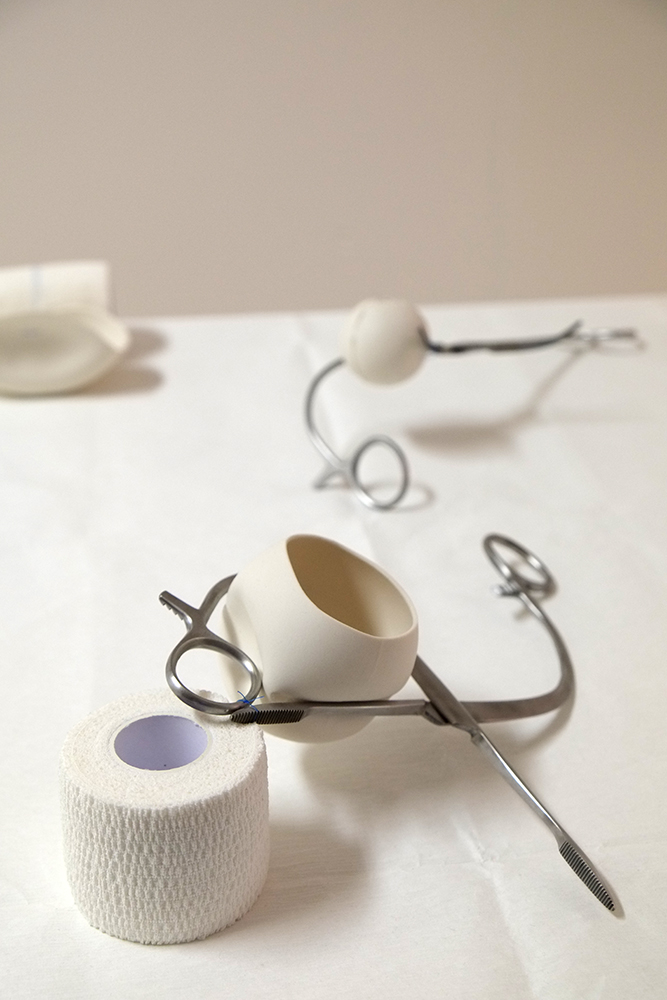 Porcelain, stainless steel surgical instrument, surgical sutures, bandage. Approx. 25cm x 25cm x 15cm