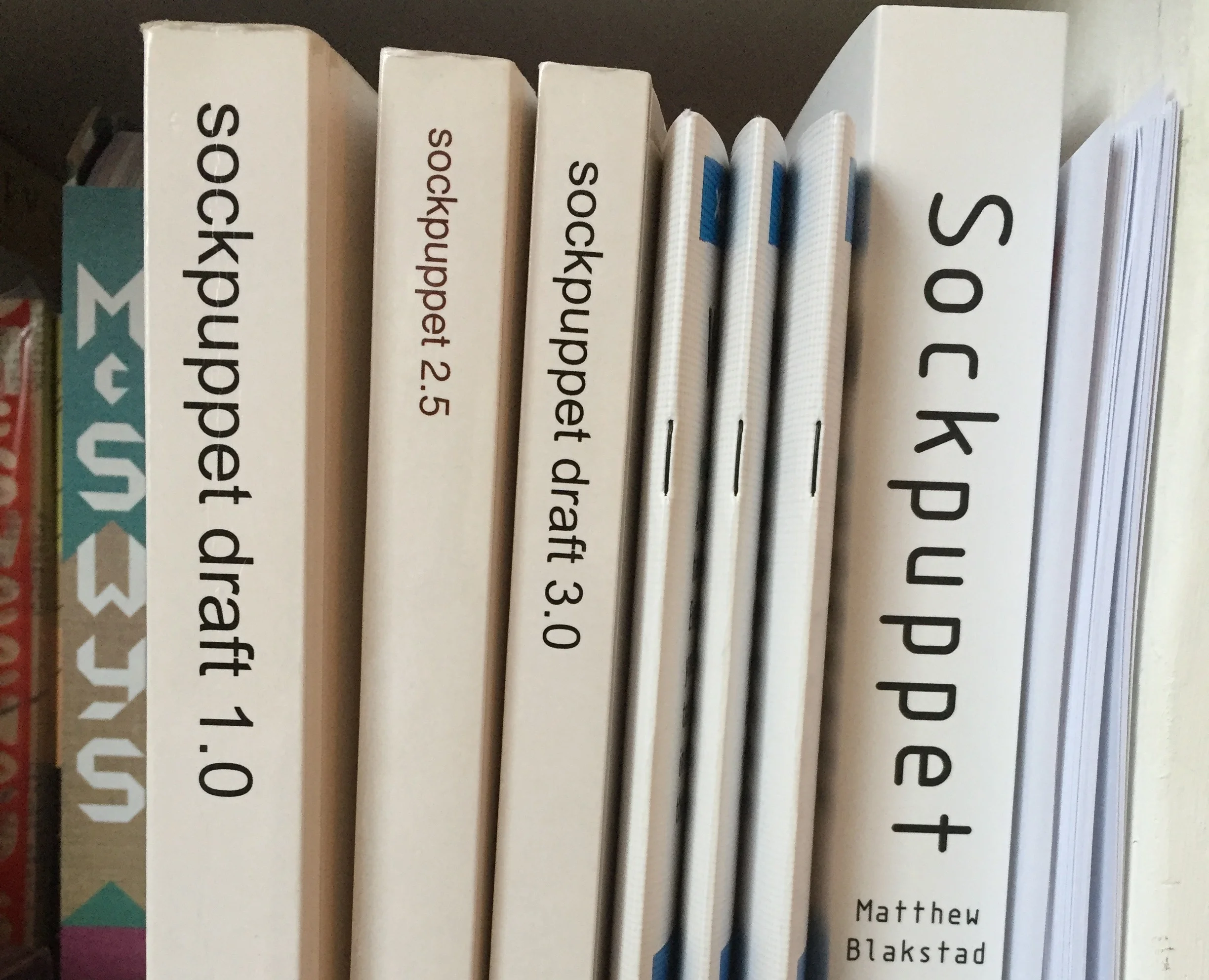 The evolution of a sockpuppet: my three draft copies sit on my shelf alongside samplers and an advance review copy produced by Hodder. Don’t ask me what happened to draft 2.0. Long story.
