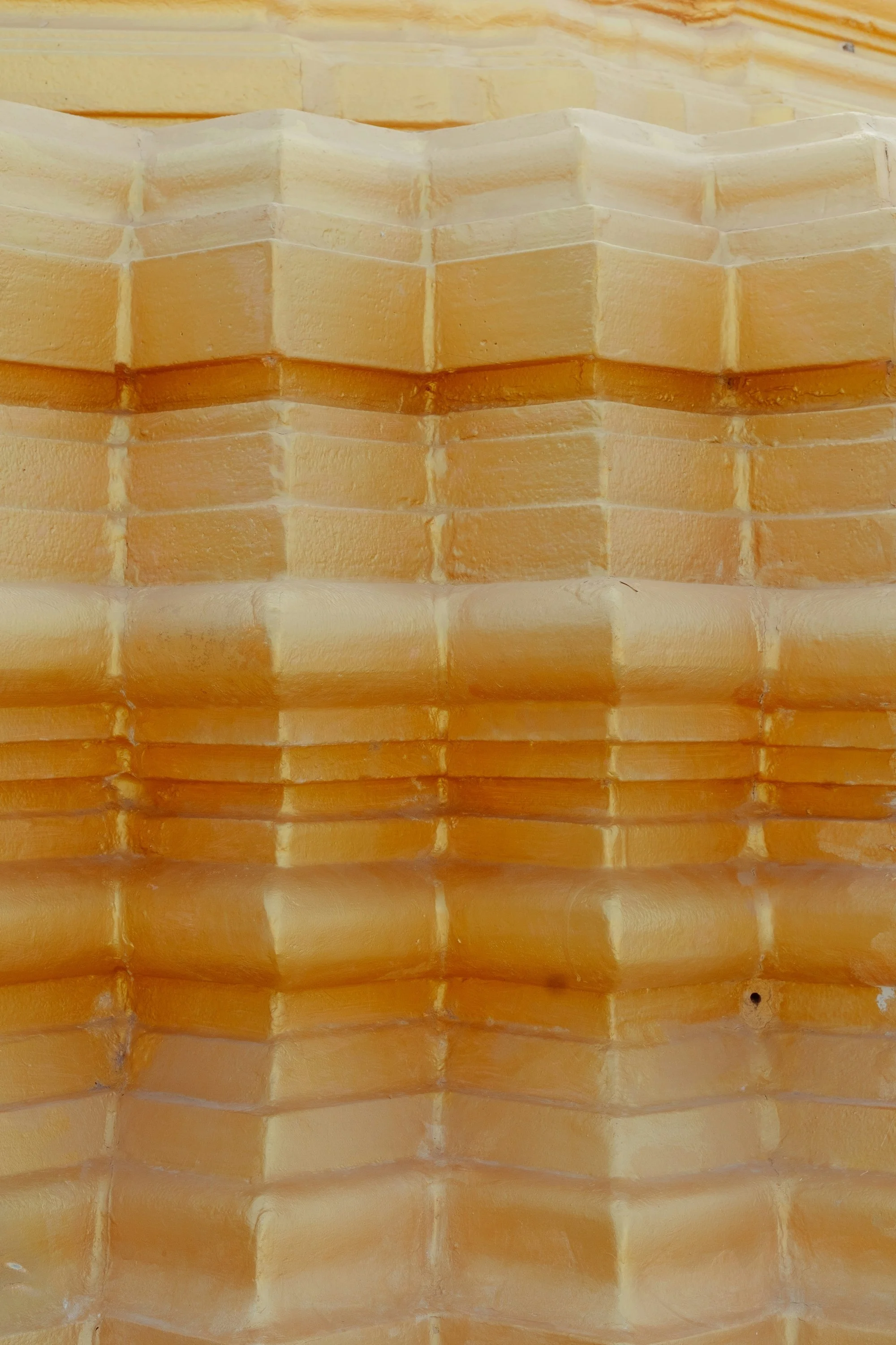 Close-up of stacked yellowish brick tiles with rounded edges.