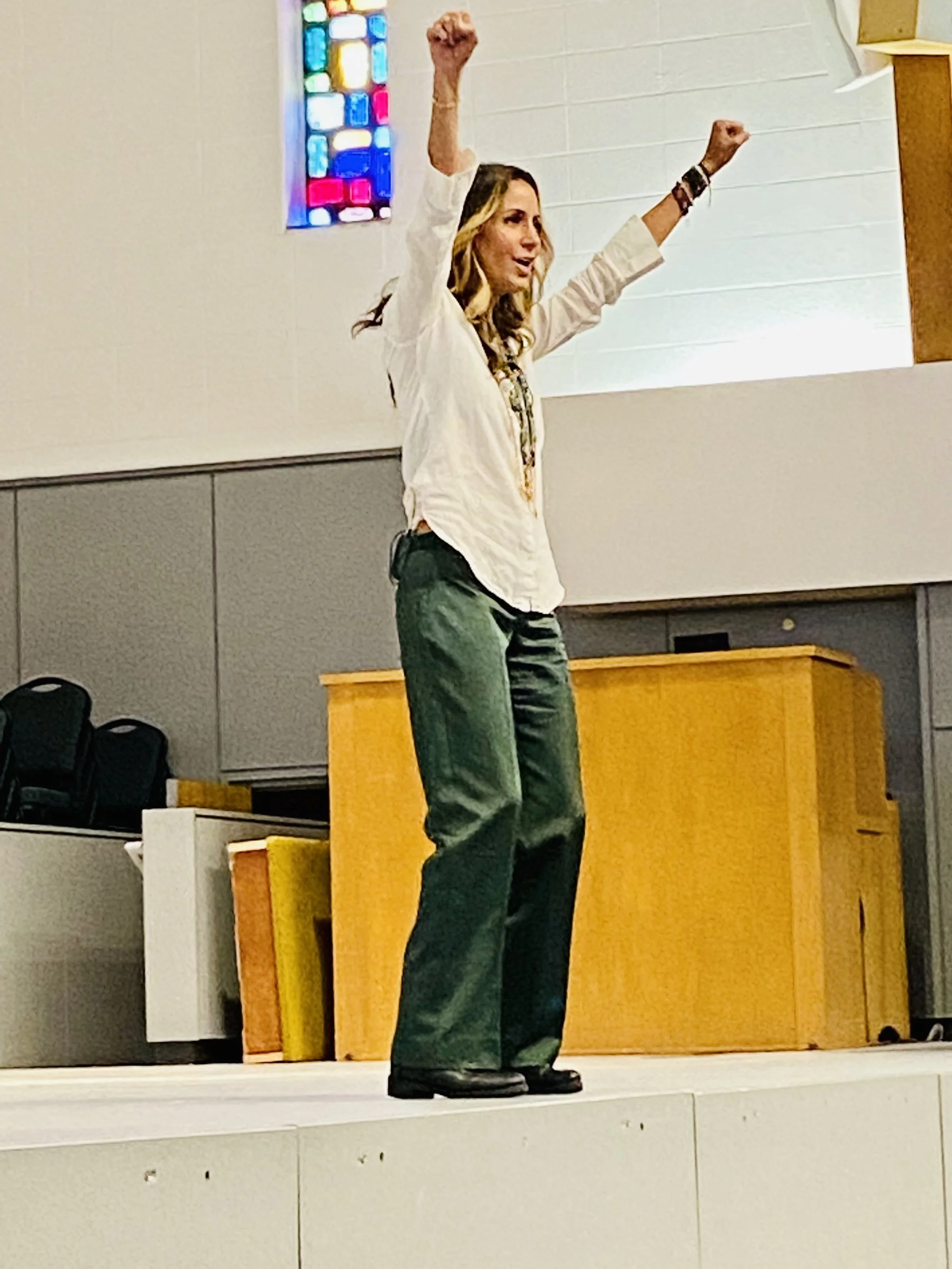 Goli Gabbay on stage with arms raised during her stress relief keynote