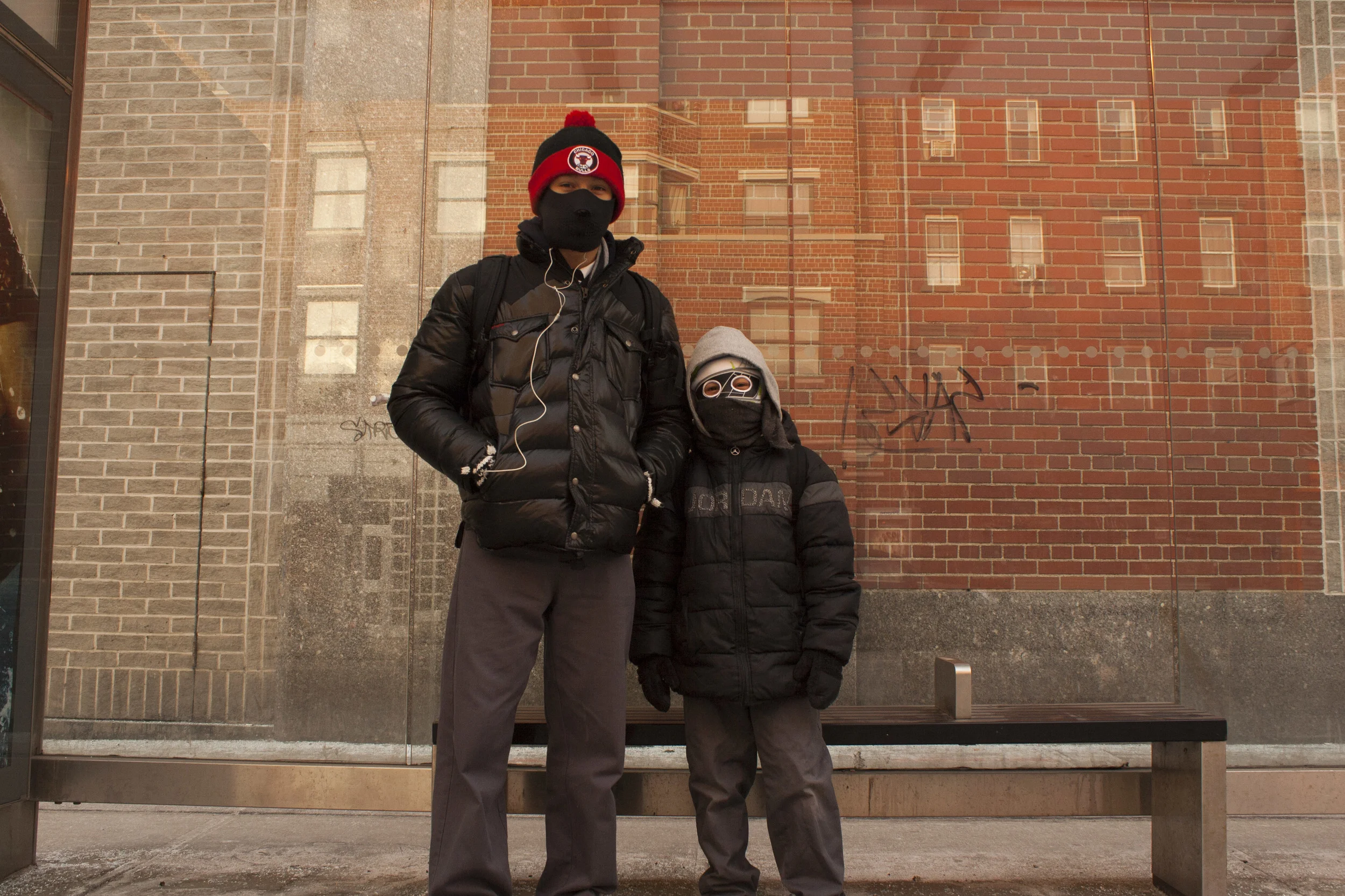 Brothers wait for the bus on a chilly winter morning. 