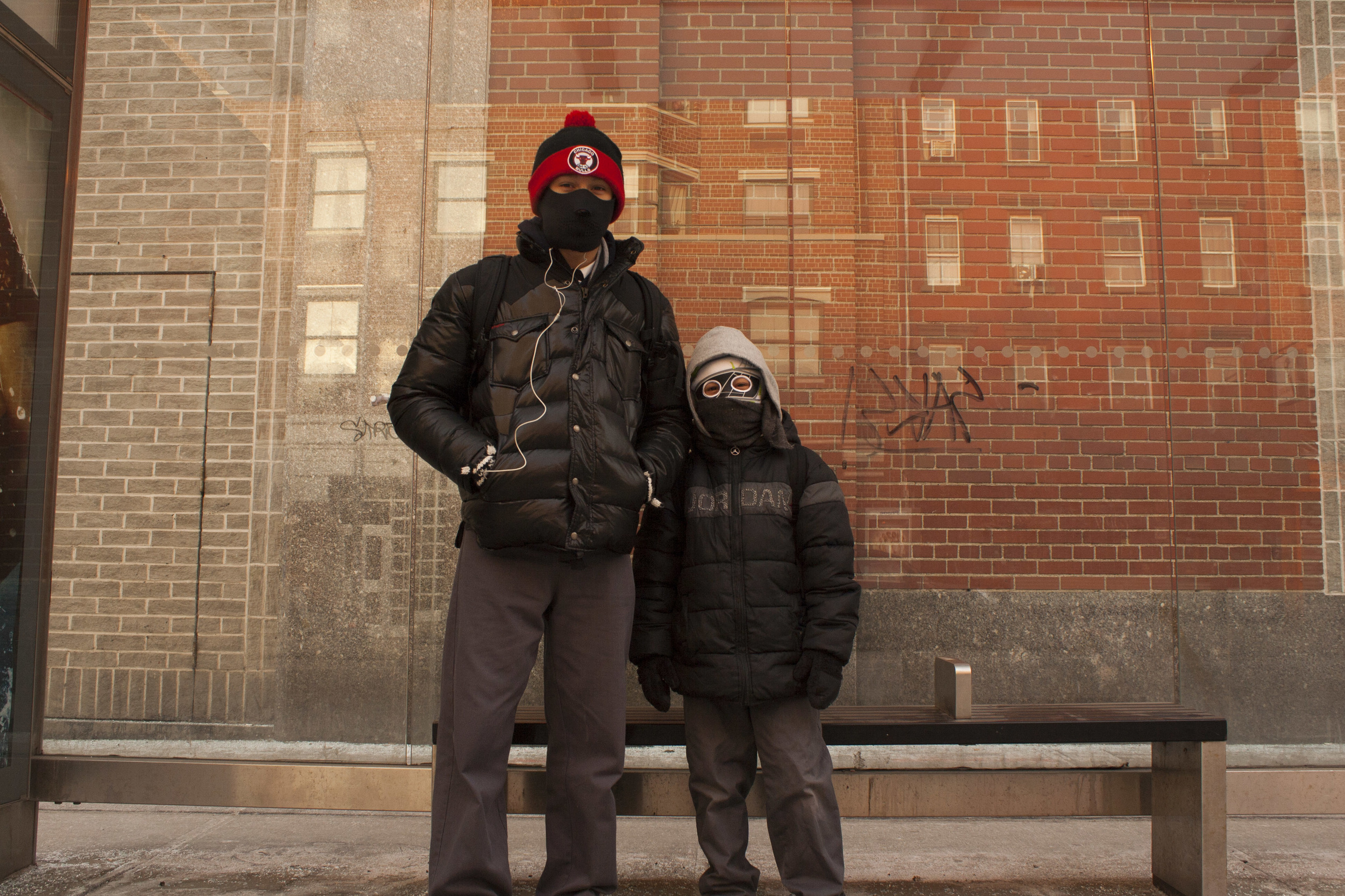 Brothers wait for the bus on a chilly winter morning. 