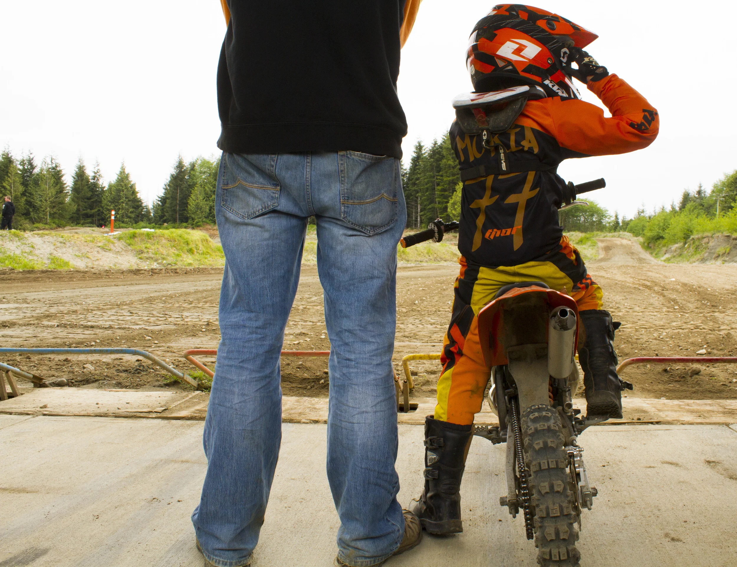 A boy and his father wait for a motocross race near Port McNeill, B.C. © North Island Gazette. 