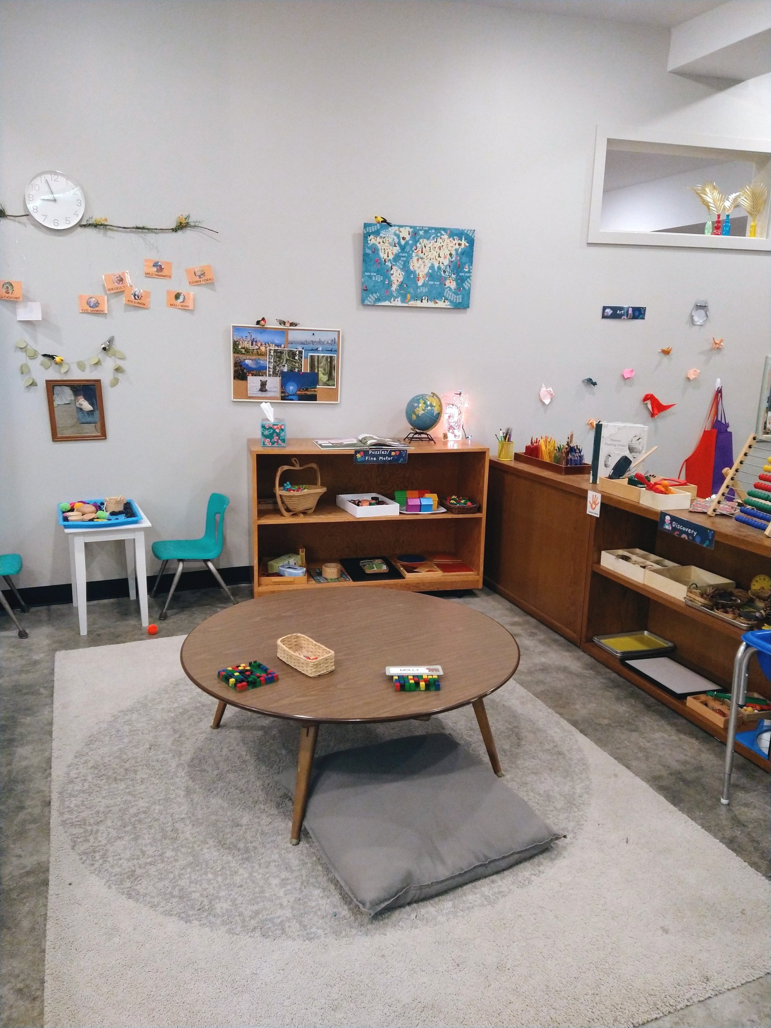  A preschool classroom with two large shelves displaying open-ended materials, and artwork hanging from the walls. 