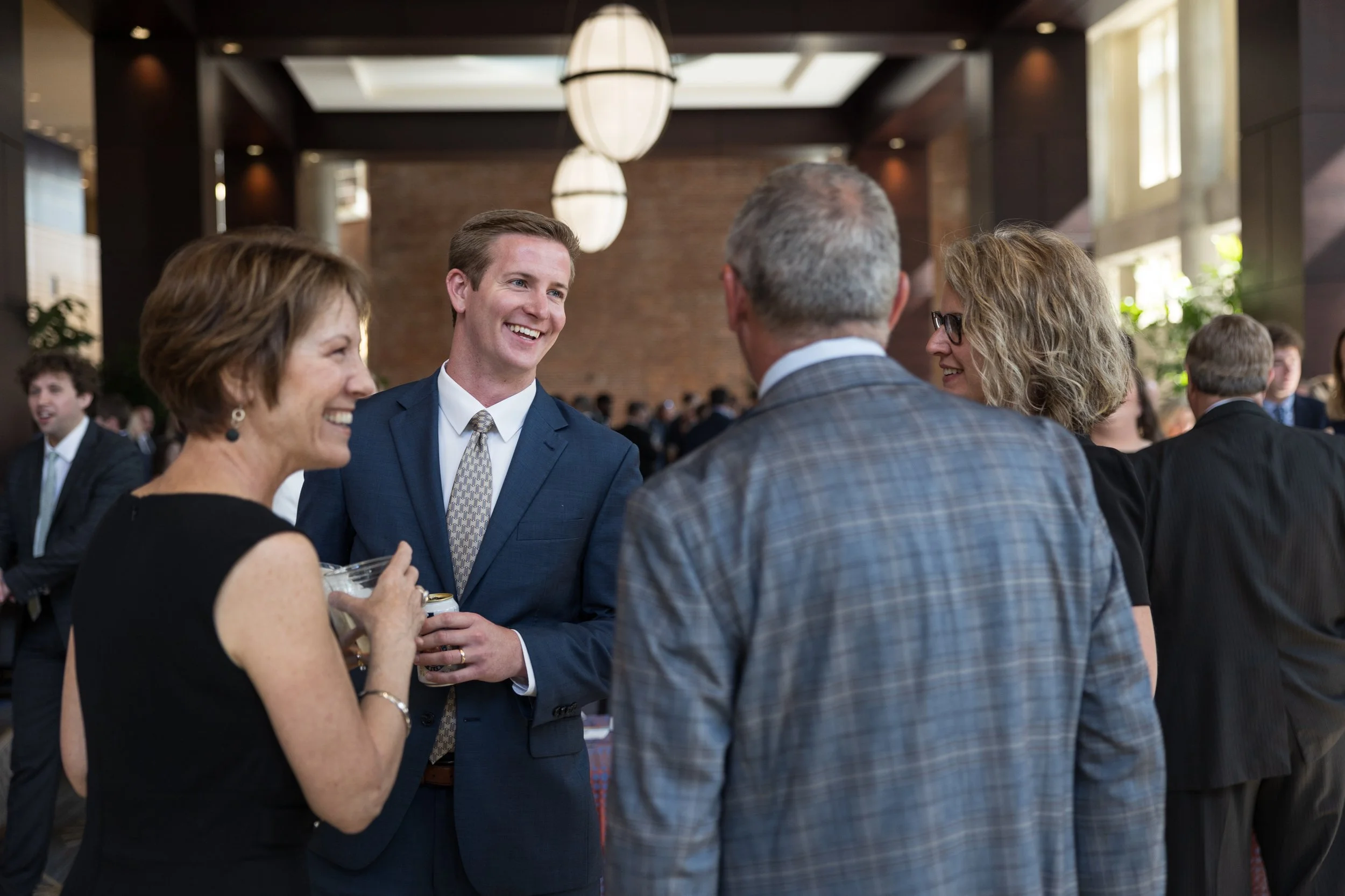 Group of five people in formal attire engaging in conversation at a social event or reception.