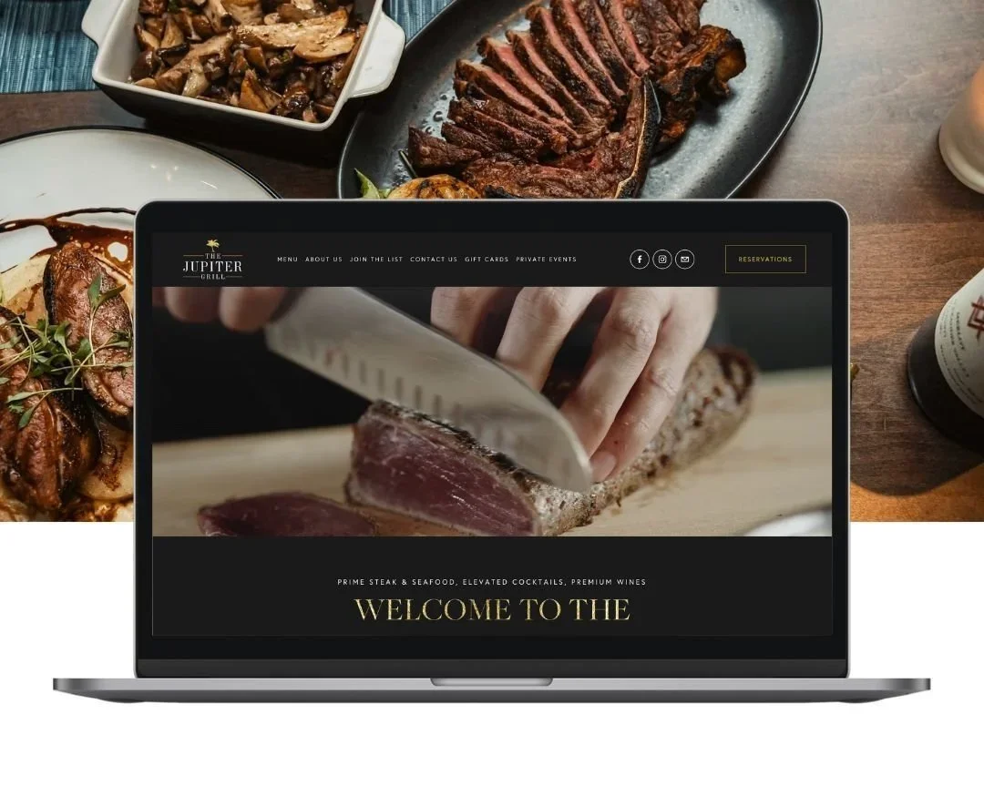 Laptop displaying the homepage of The Jupiter Grill restaurant, featuring a chef slicing a steak.