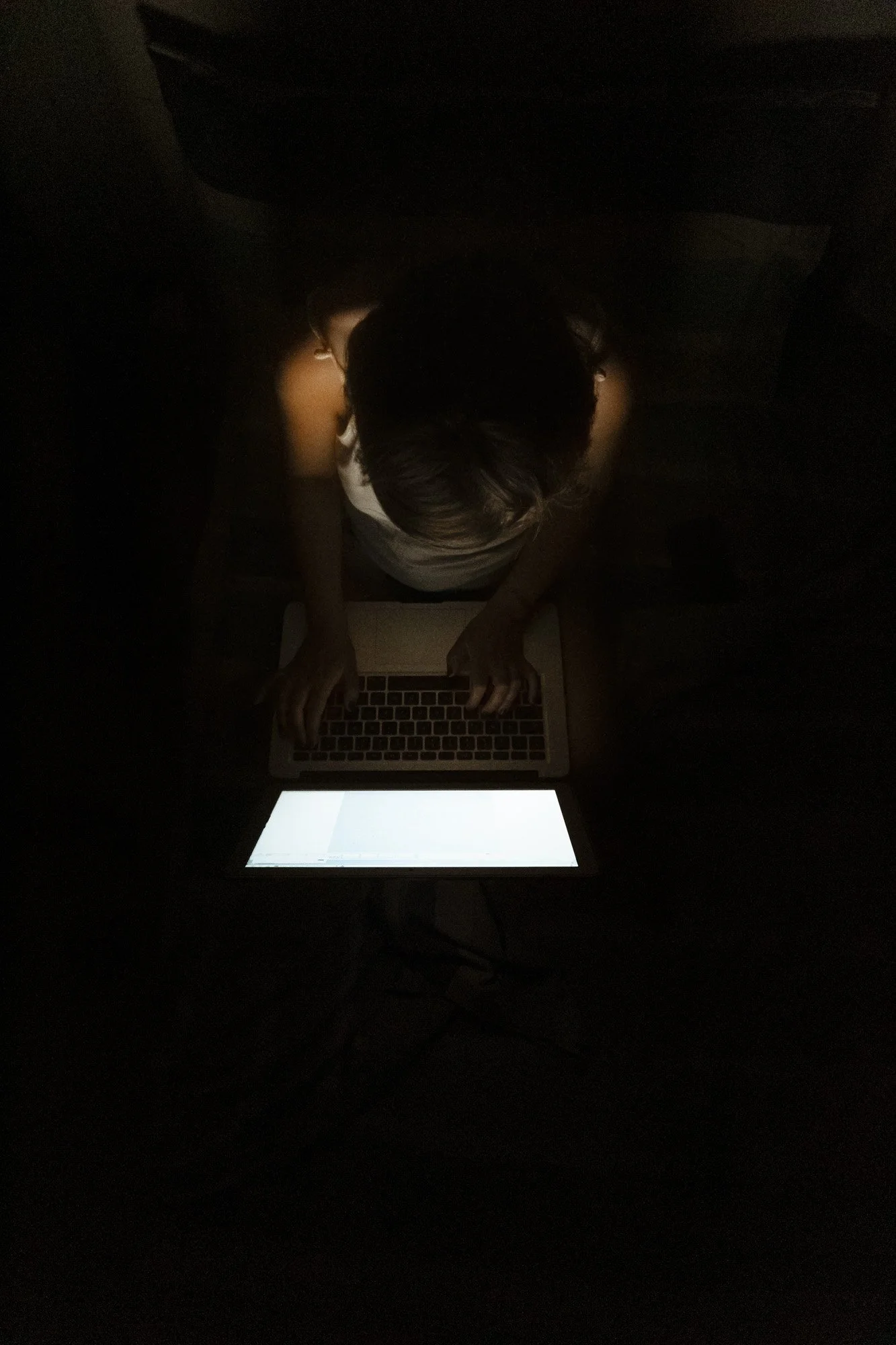female-freelance-worker-sitting-dark-room-typing-laptop.jpg