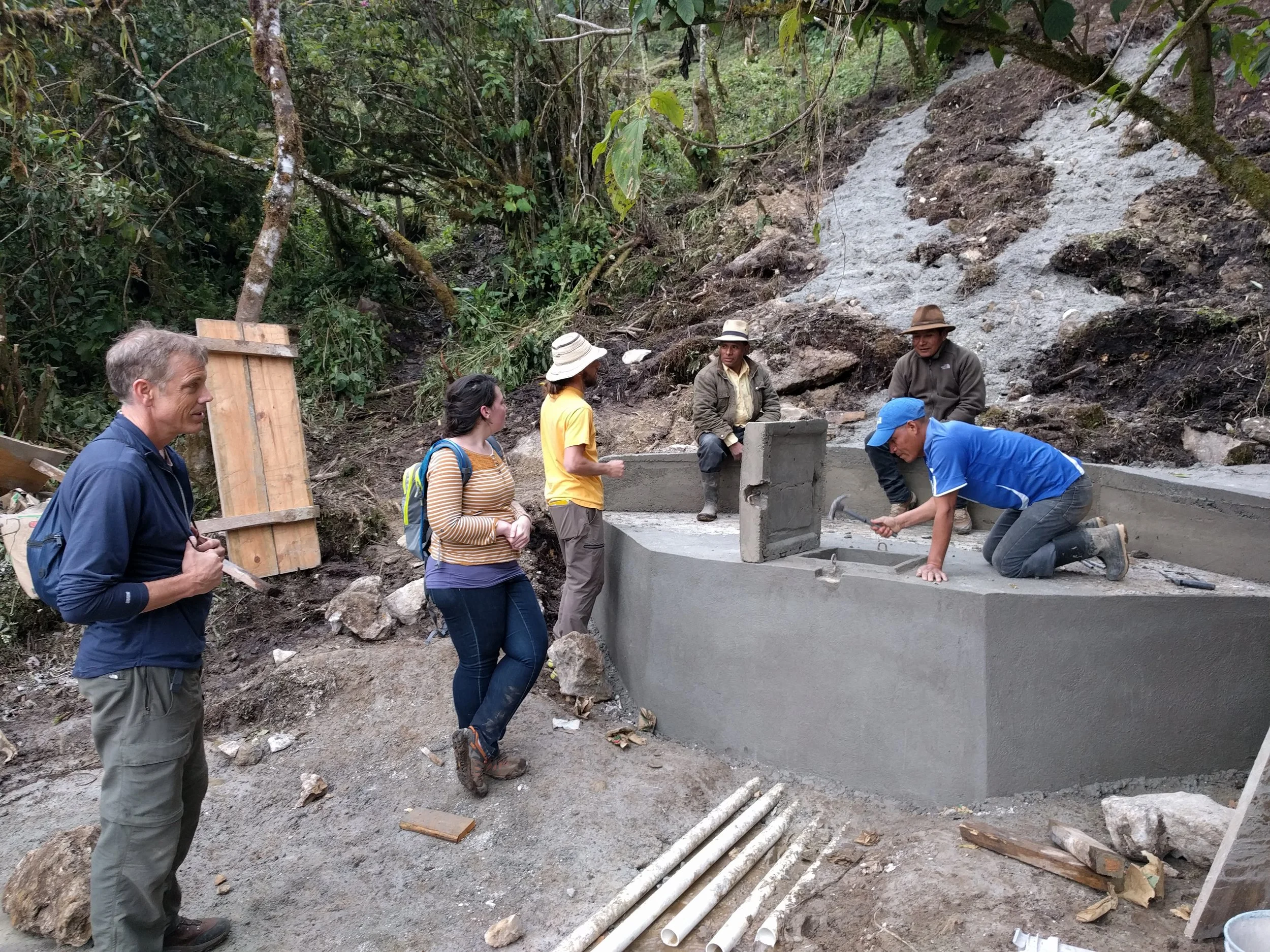 RMP members, water committee president, and masons Christobal and Antonio taking the formwork off the catchment basin at the new spring.