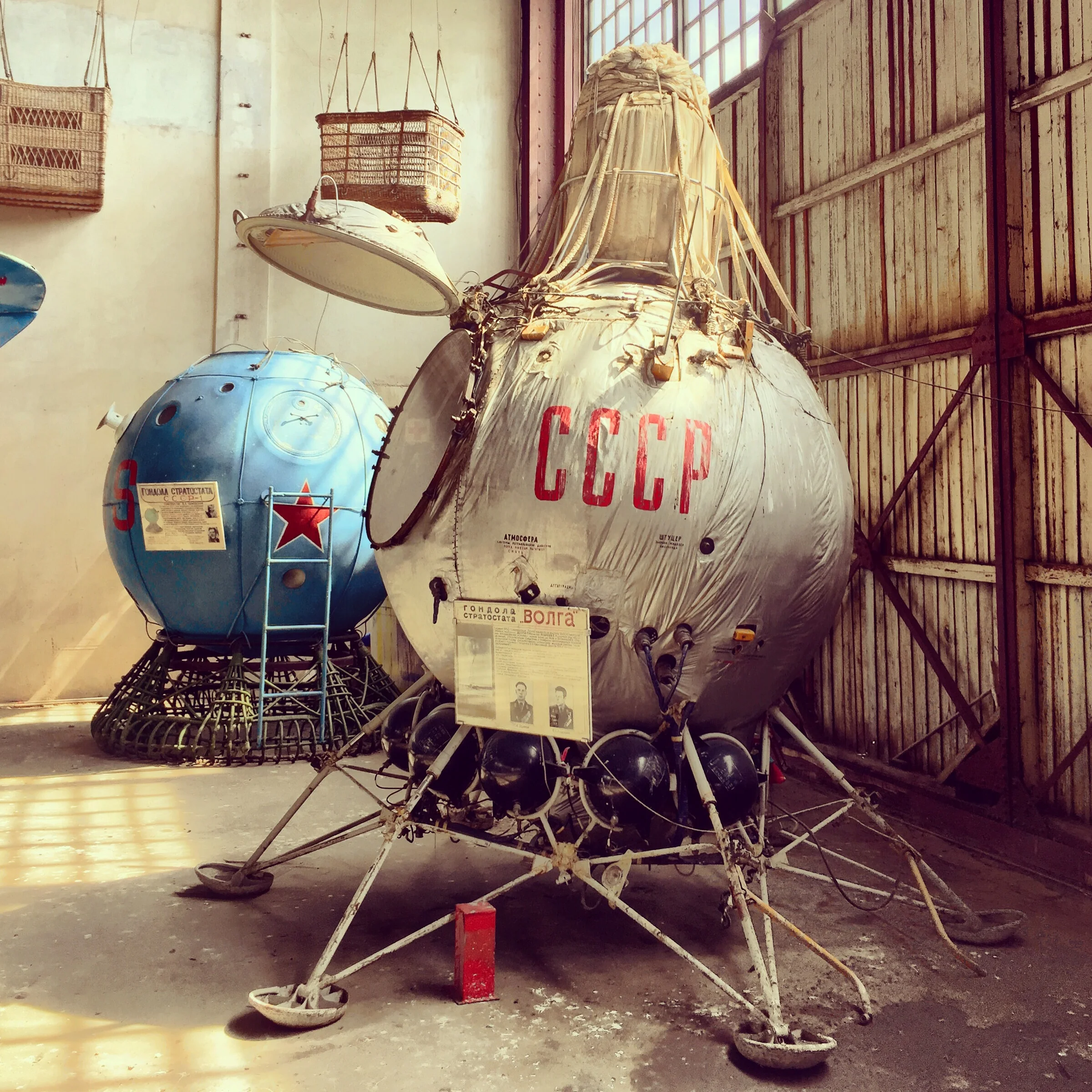 Cápsula espacial meio que jogada num canto de um grande galpão. 