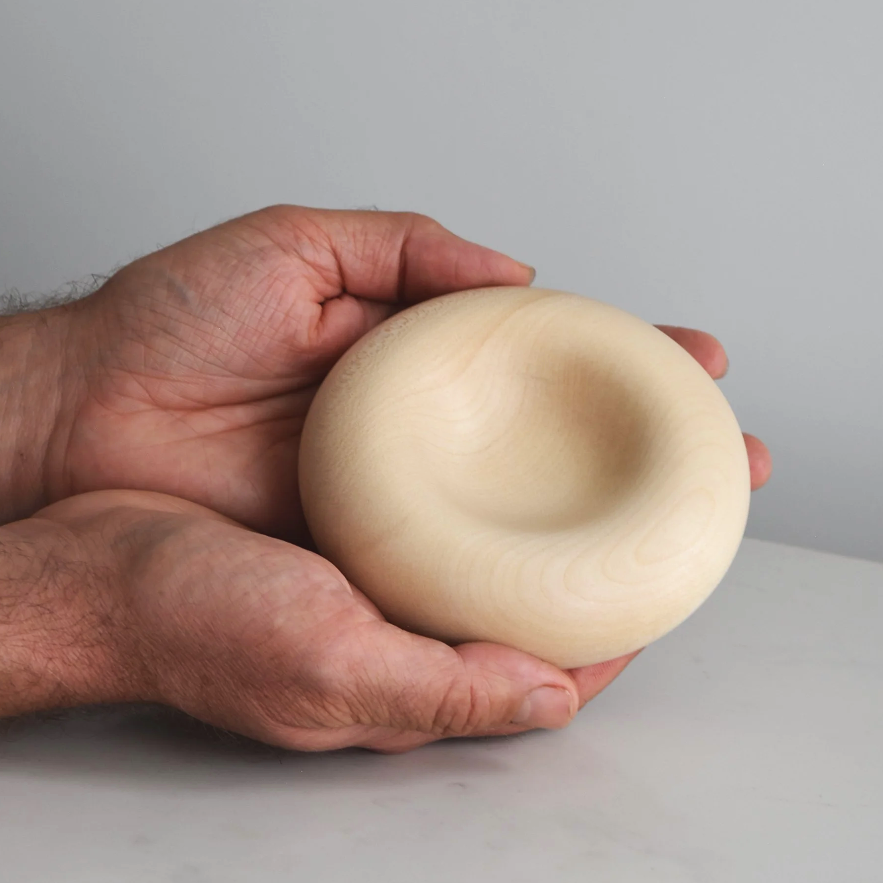 Medium Deep Pillow in Sycamore, hand-turned wooden piece by Bird & Branch, product with hands  photo