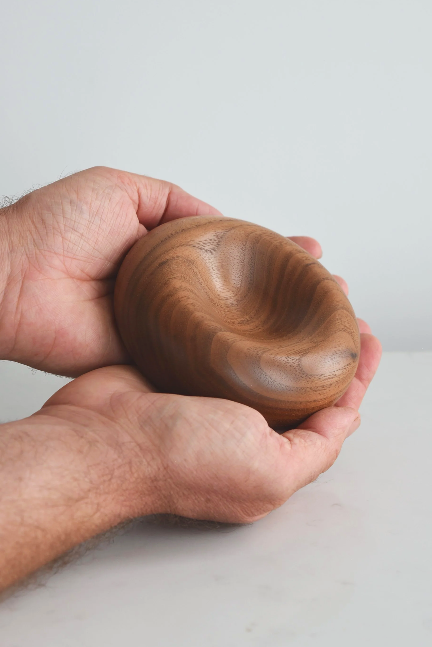 Medium Deep Pillow in American Walnut, hand-turned wooden piece by Bird & Branch, main product photo with hands for scale