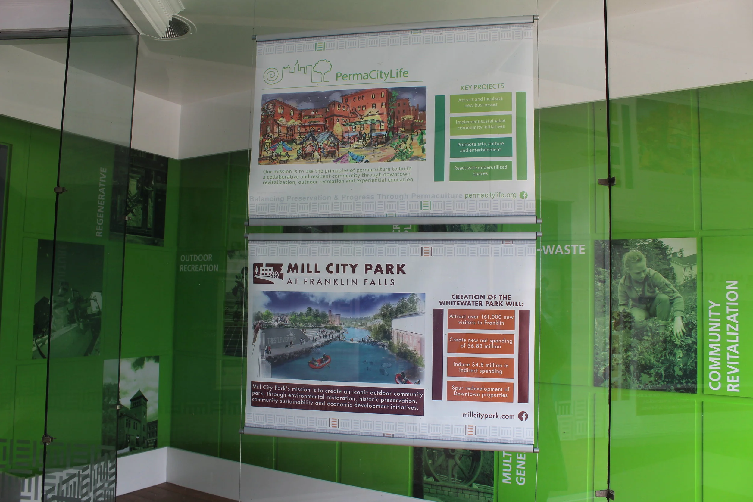 Melanie Patria's designs for advertising PermaCityLife and Mill City Park hanging in the SLI storefront (The Hub at 357 Central Street in downtown Franklin.