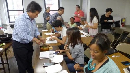 李宗保按照諾德霍夫記載的食物清單為大家烹飪,現場中、西、非裔混血客家後代們品嘗美食,熱烈討論。(蔡溶/大紀元)