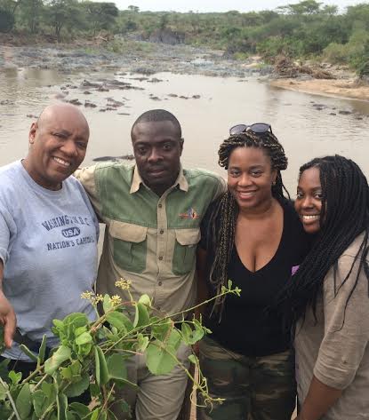 With our safari guide in Serengeti, photobombed by wading hippos