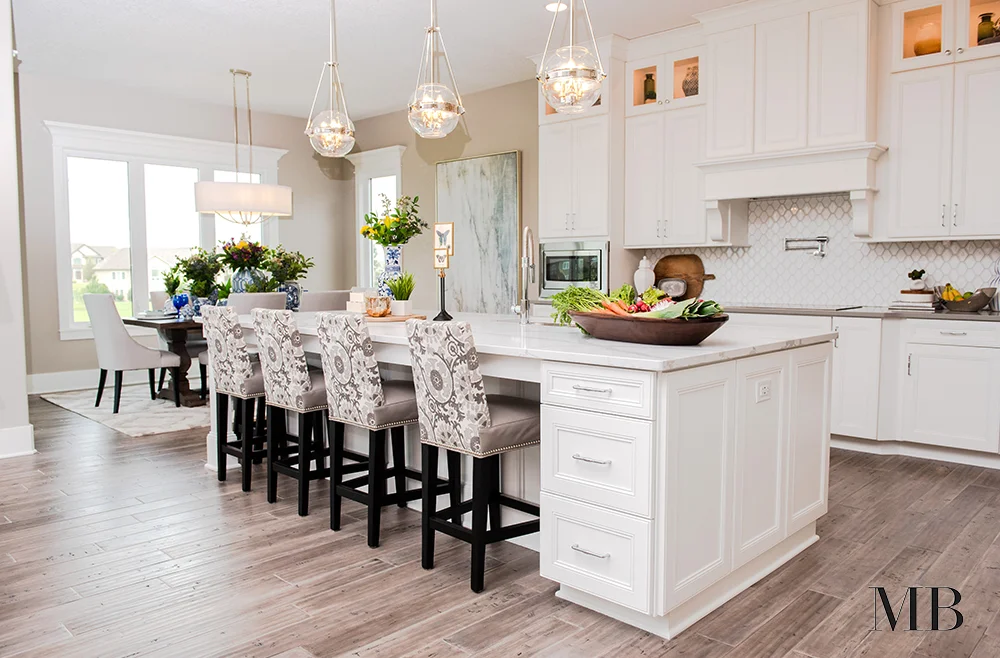 A luxe kitchen can be hard to pull off when it's part of a great room. Intricate detailing in the cabinetry, hardware and lighting, the extras make the space feel set apart while the neutral color palette and efficient footprint keep it from being distracting from the other spaces.