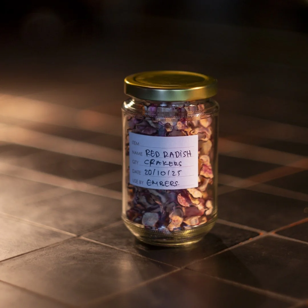 Jar of dried red radish crackers with a label reading item, name, date, quantity, and usage, placed on a tiled surface.
