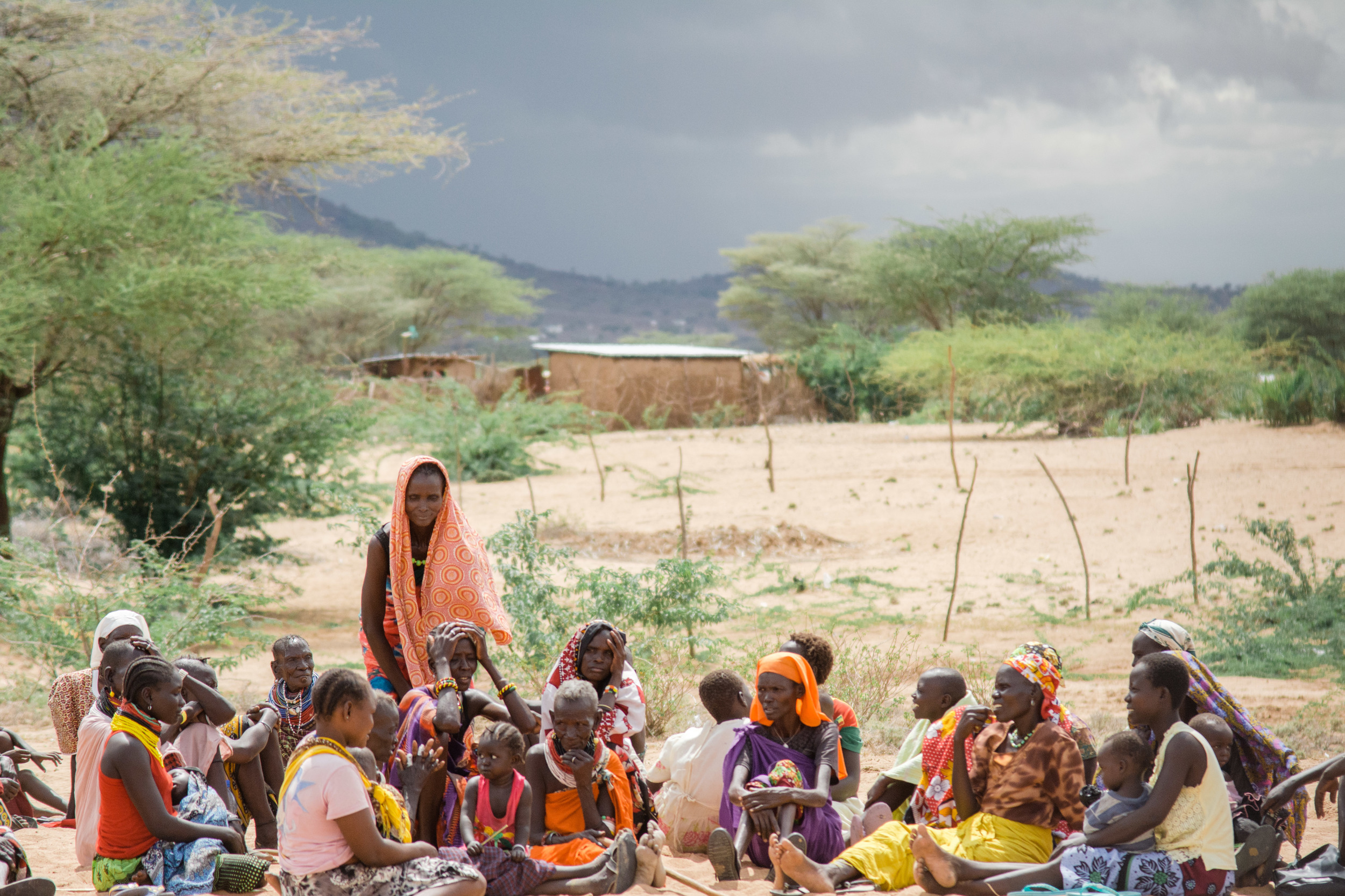A group of women sit together outside as they wait to be seen 