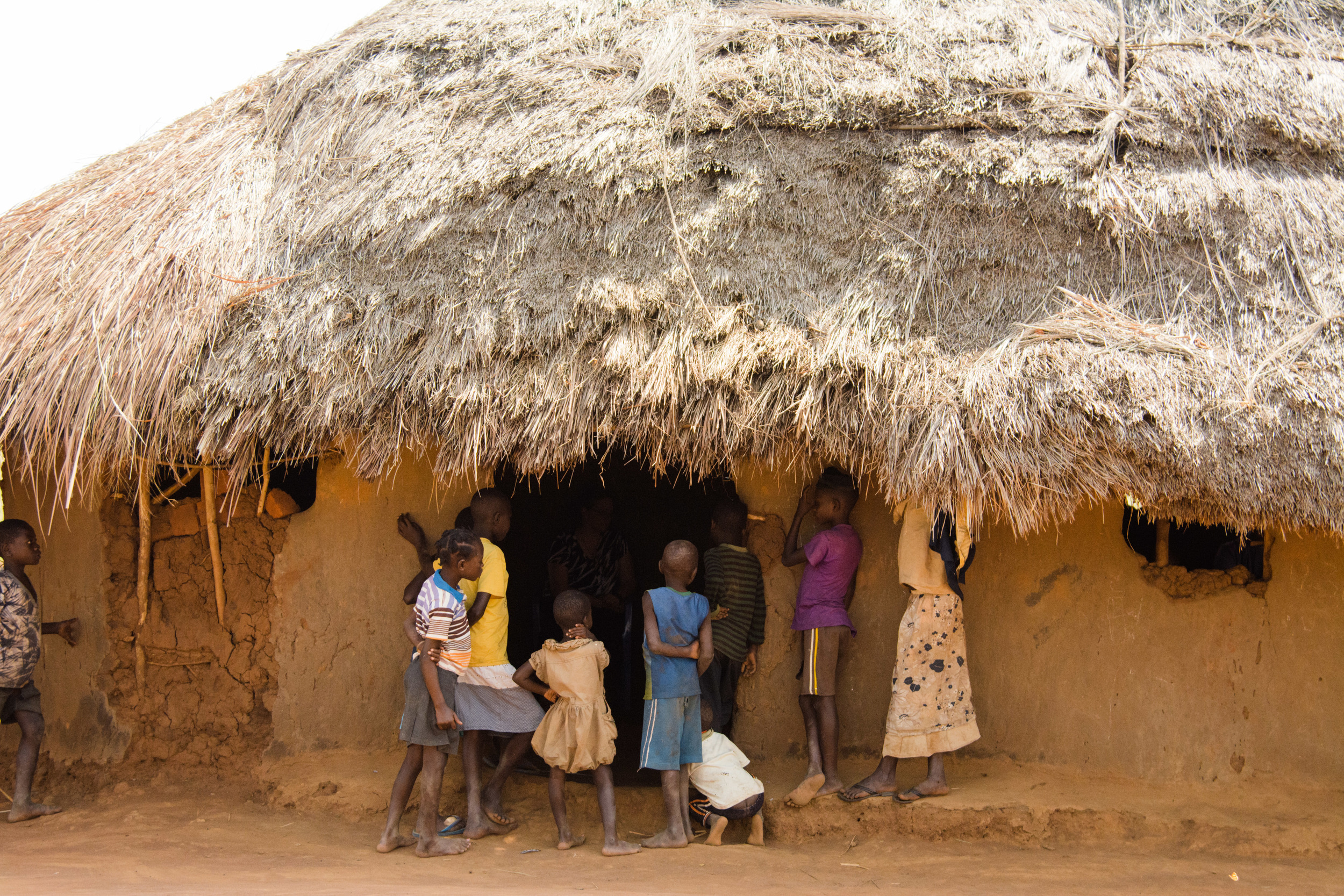 Children peering into a building that serves as a church as American missionaries talk with local church leaders.