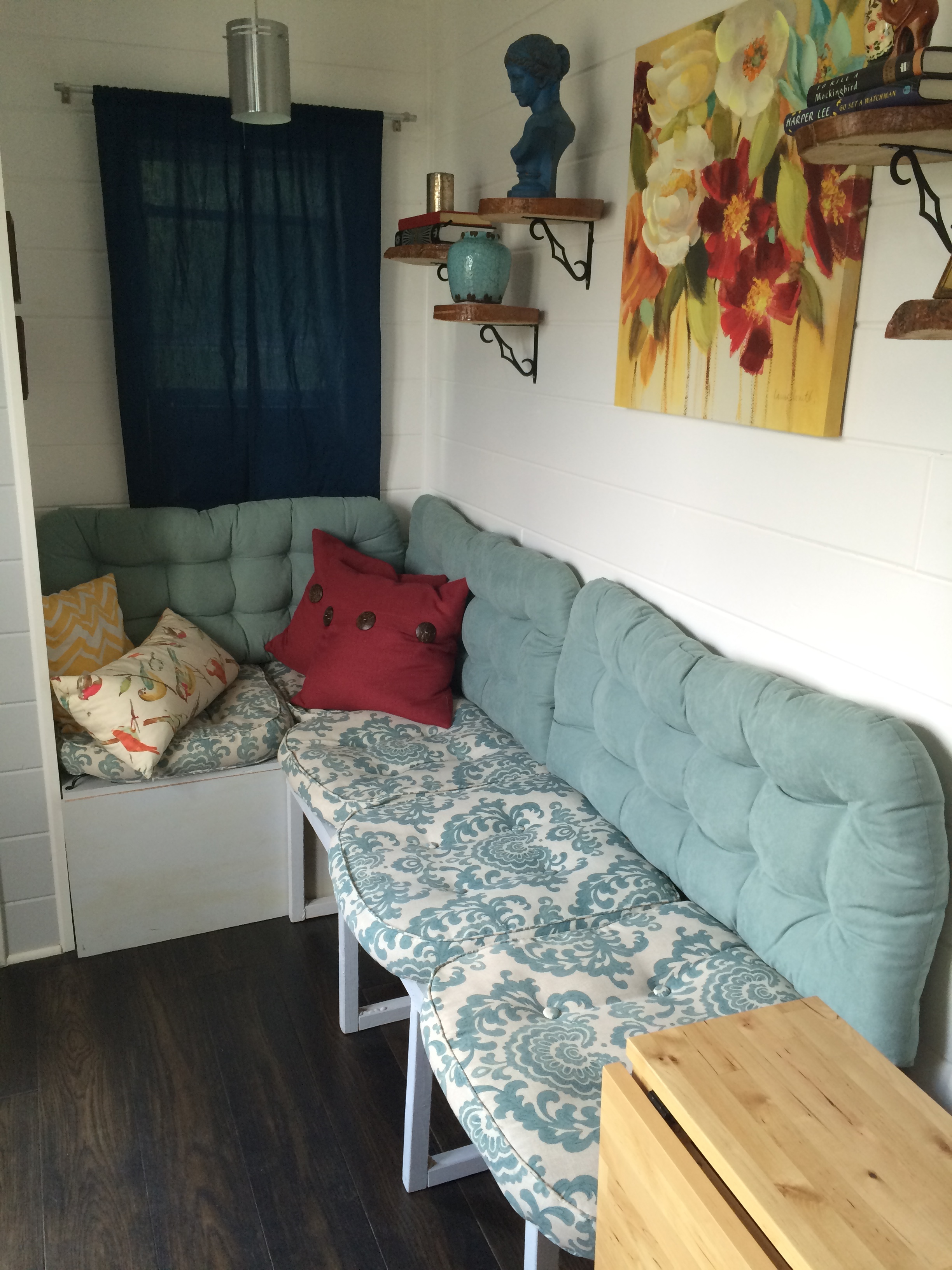  We built this L-shaped bench to hide our water tank (behind the gray panel in the "nook" part of the bench. We also have two black leather cube footstools that slide under the bench that we can store winter hats and scarves in. 