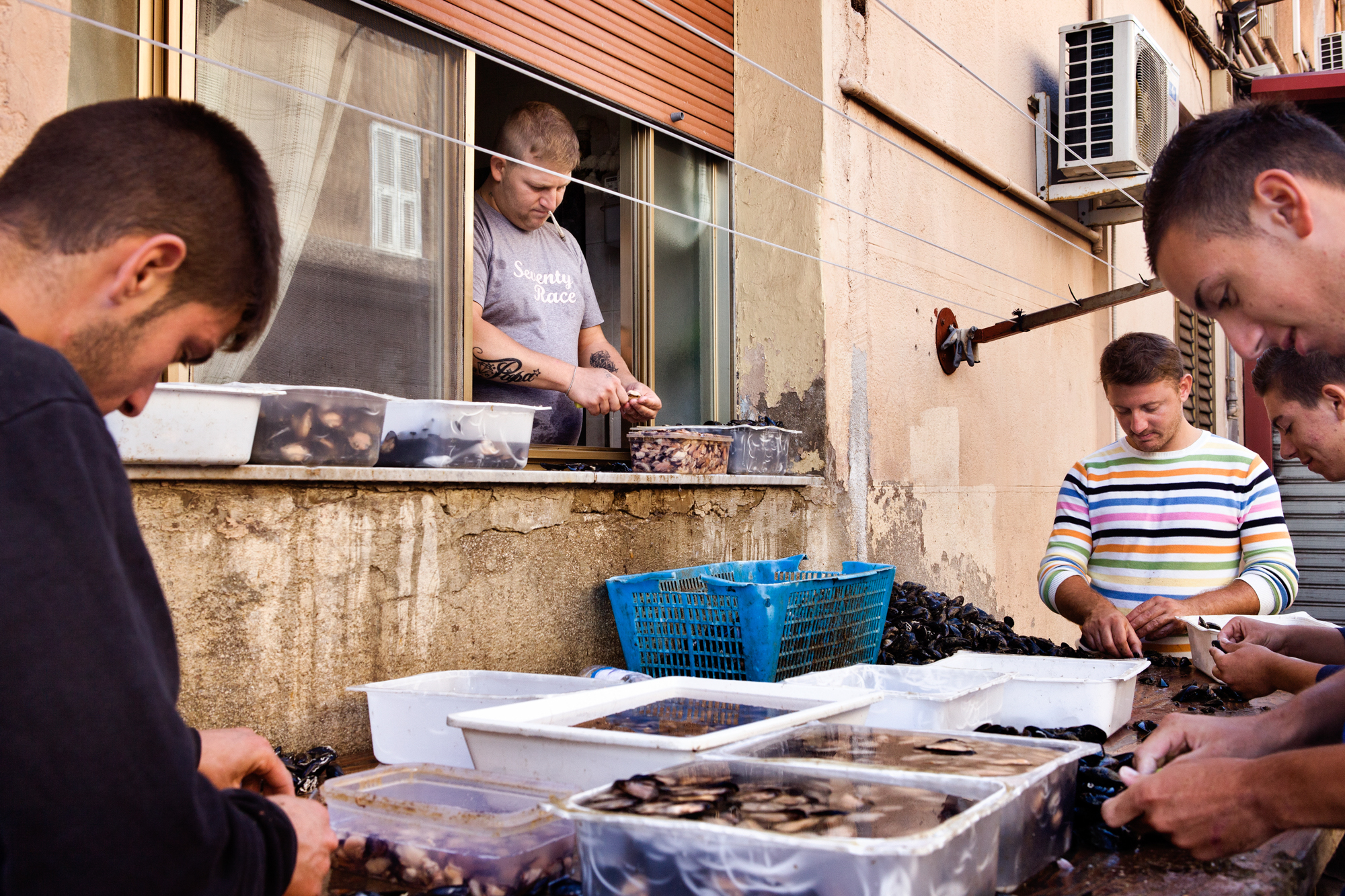  Taranto, Italia, 26 Settembre 2013. Armando e i suoi amici puliscono le cozze nella Città Vecchia. Armando è agli arresti domiciliari, per questo motivo lavora dalla finestra di casa. Nel 2012, a causa dell’alta concentrazione di diossina e Pcb rile
