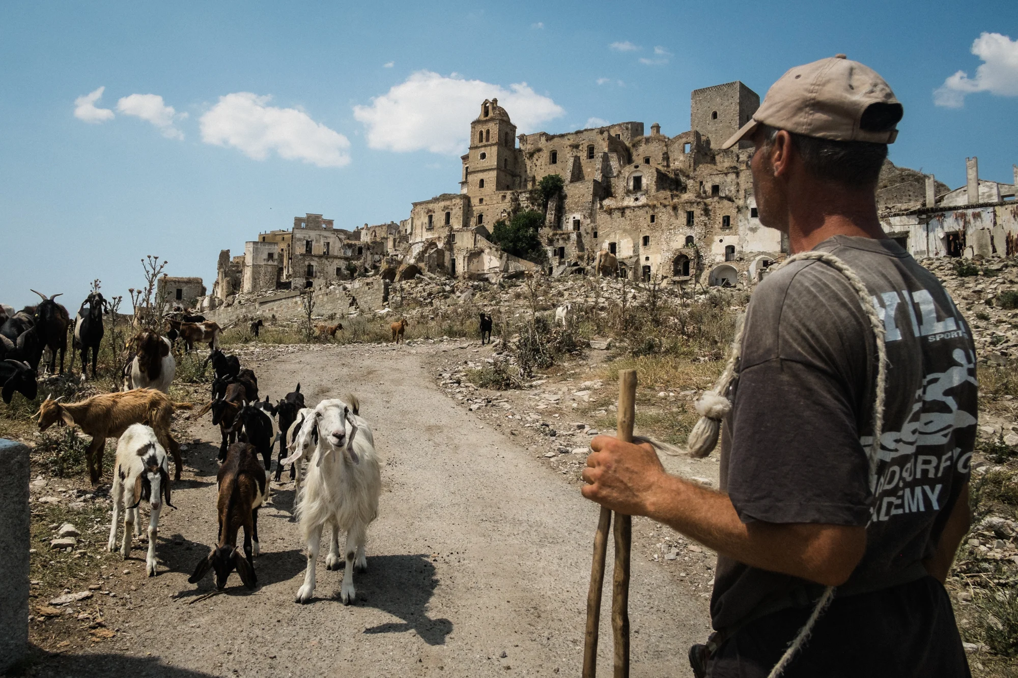 Un pastore col suo gregge a Craco (MT), 2015. Craco è chiamato il paese fantasma perché nel 1963, a causa di una frana di vaste proporzioni, i suoi duemila abitanti furono costretti a evacuare per trasferirsi a valle. Oggi il paese è meta turistica e numerosi registi lo hanno scelto per girare alcune scene dei loro film, come Cristo si è fermato a Eboli di Francesco Rosi. 