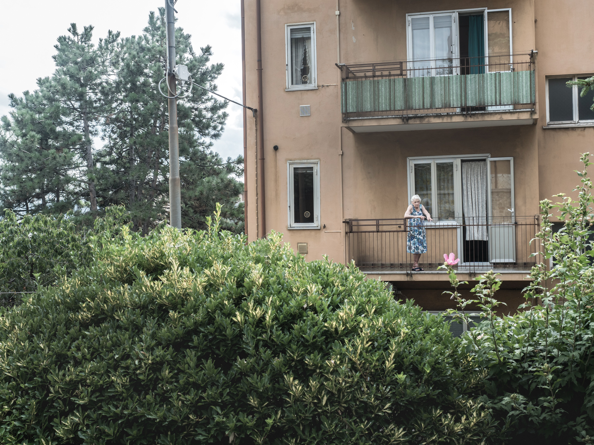  Un'anziana si affaccia dal suo appartamento nel rione di Servola, alle spalle della sua abitazione sorge l'impianto siderurgico, Trieste 2015. 