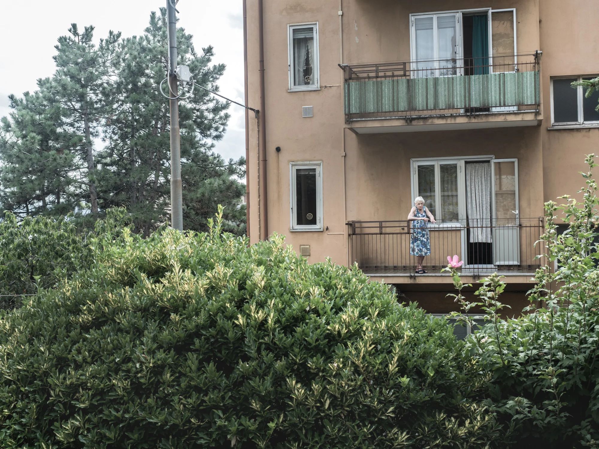 Un'anziana si affaccia dal suo appartamento nel rione di Servola, alle spalle della sua abitazione sorge l'impianto siderurgico, Trieste 2015.