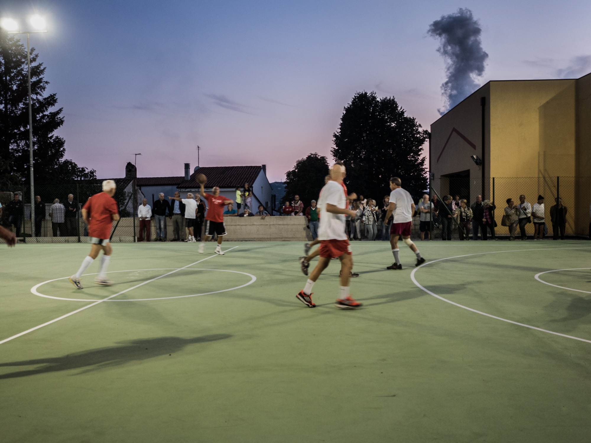  Partita amichevole nel nuovissimo campo di pallacanestro all'aperto nel rione Servola di Trieste, alle spalle una delle "fumate nere" dell'adiacente Ferriera.&nbsp;Trieste, 2015. 