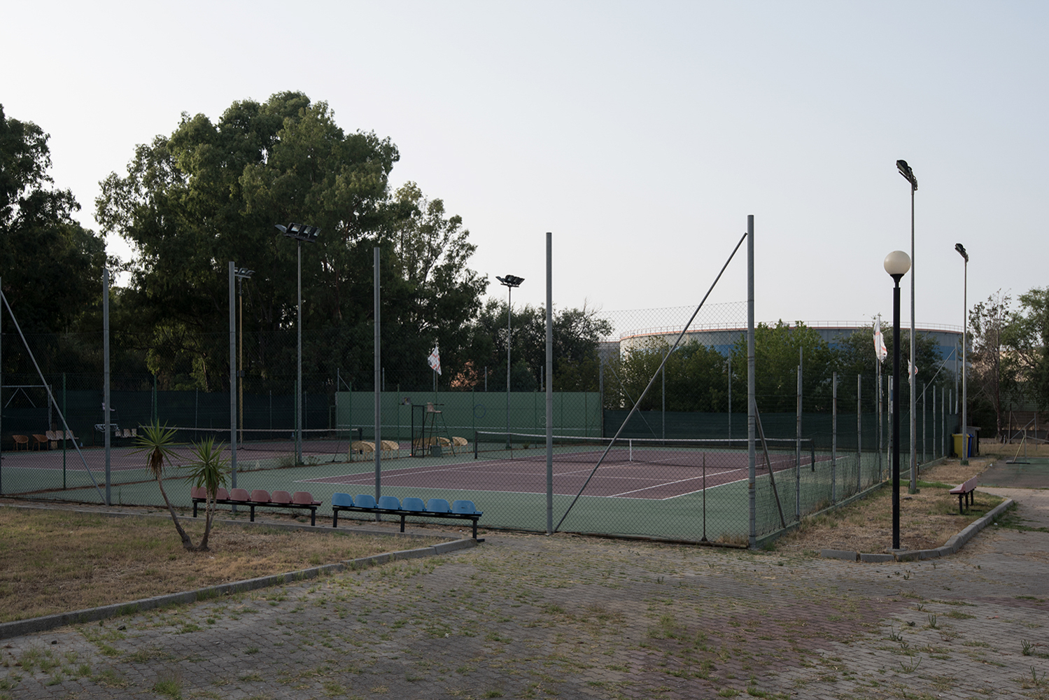  Palestre e campi sportivi sorgono a ridosso di imponenti cisterne disposte lungo i confini della raffineria. Sarroch (Cagliari), 2017 