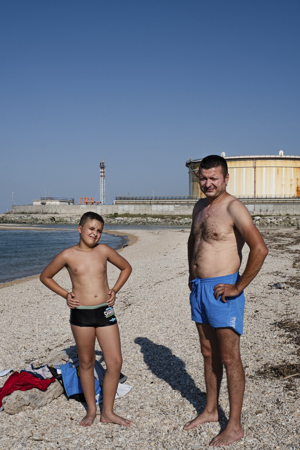  Mihael e suo figlio, sono di origine rumena e vivono a Jesi e frequentano spesso la spiaggia vicina alla raffineria Api. Falconara Marittima (Ancona), 2023. 