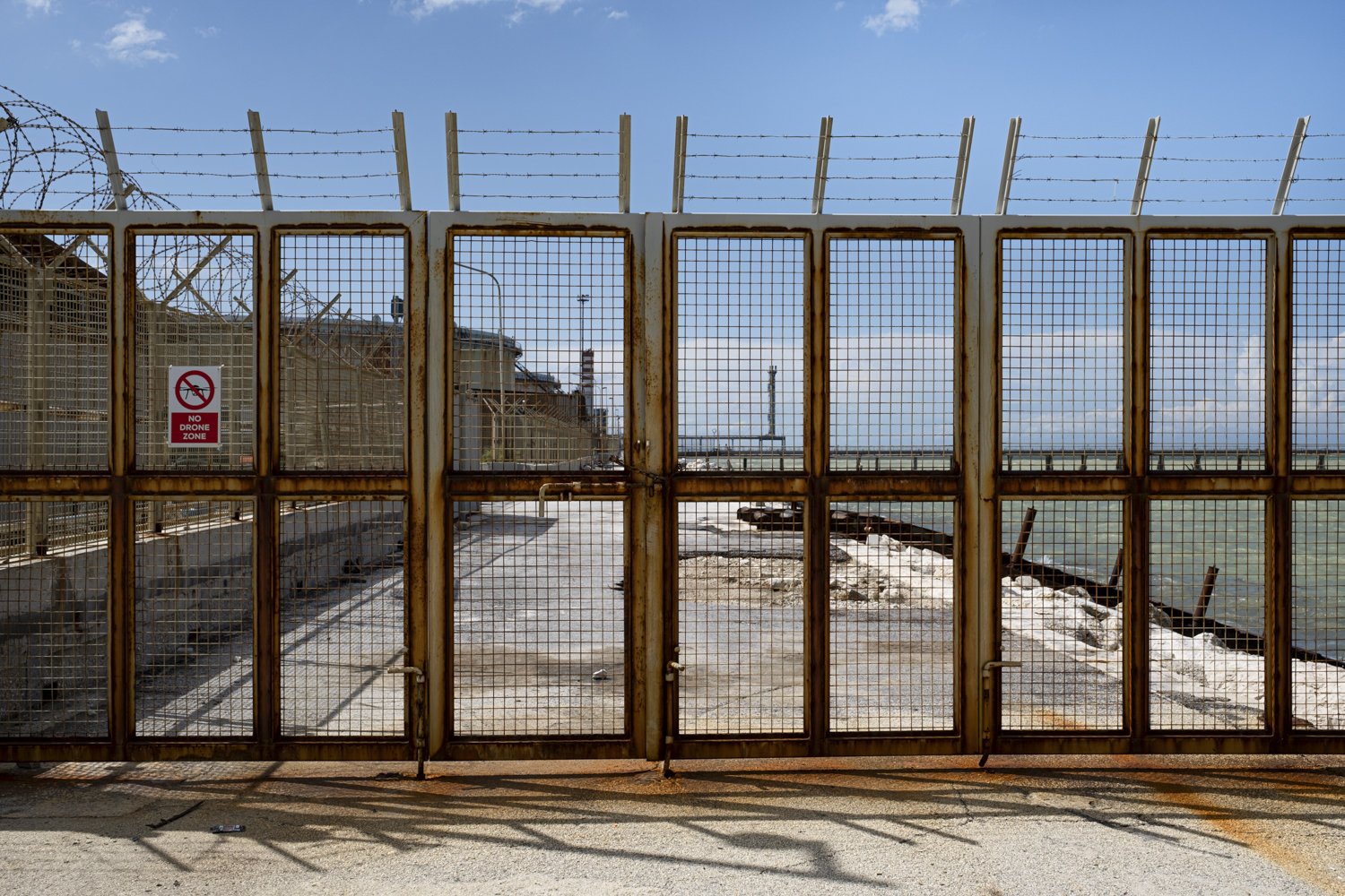  Cancello sul perimetro della raffineria API. Falconara Marittima (Ancona) 2023. 