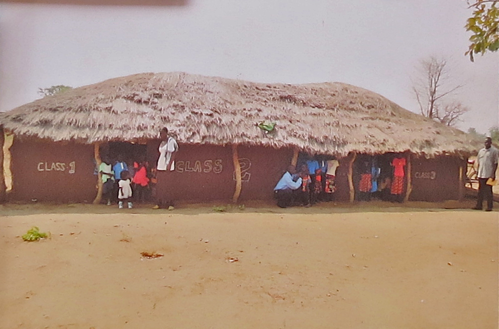 Three temporary classrooms - grass roofs, mud walls, pole supports