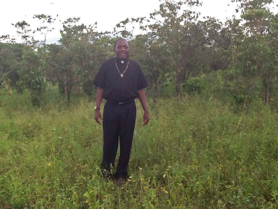 Bishop Tom standing in the newly acquired piece of land from the community to construct the primary section.jpg