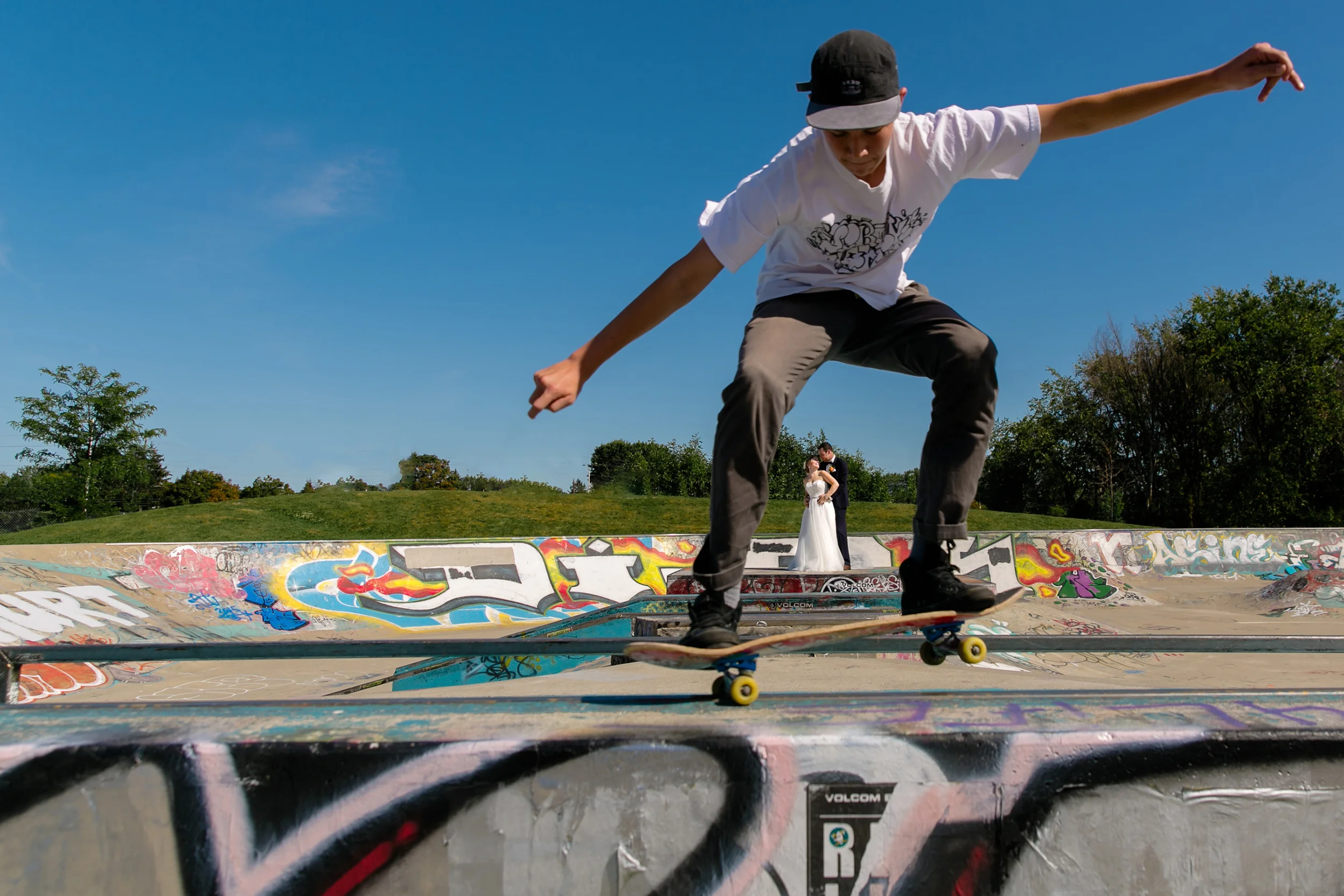 Bride and groom portrait at a skate park with skateboarder