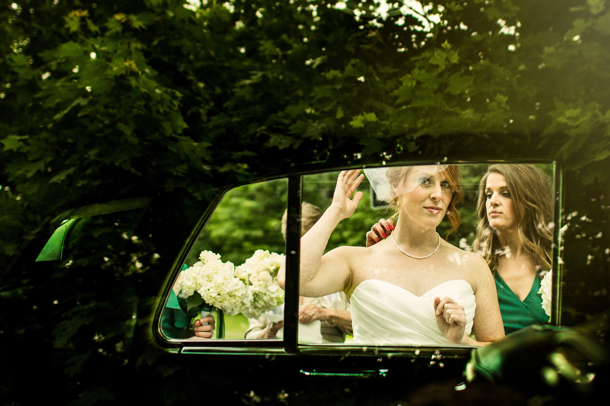 bride adjusts hair in the reflection of a limo window before a rockcliffe park pavilion wedding ceremony