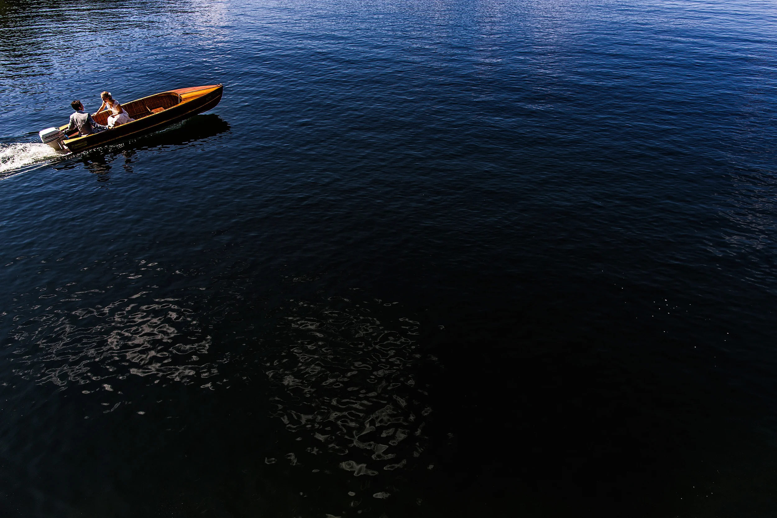 bride and groom ride in a boat on their way to wedding reception