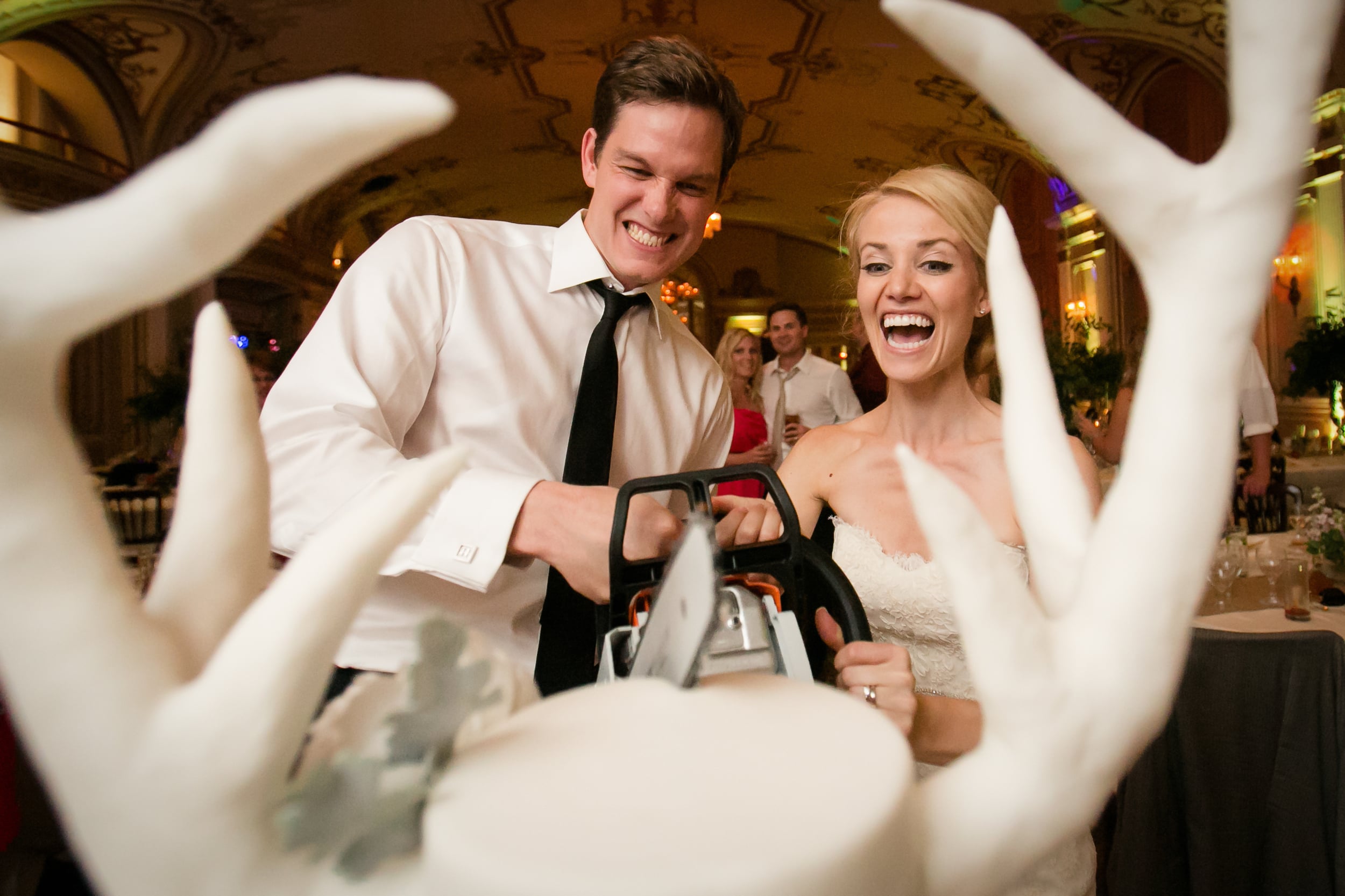 bride and groom cutting their cake with a chainsaw