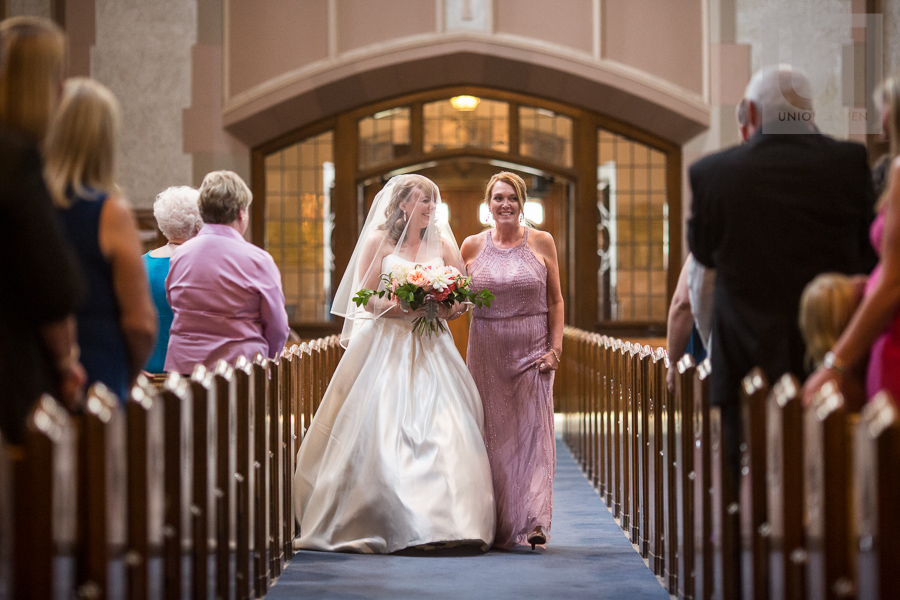 bride-laughing-while-walking-down-church-aisle-with-mother-at-ottawa-wedding