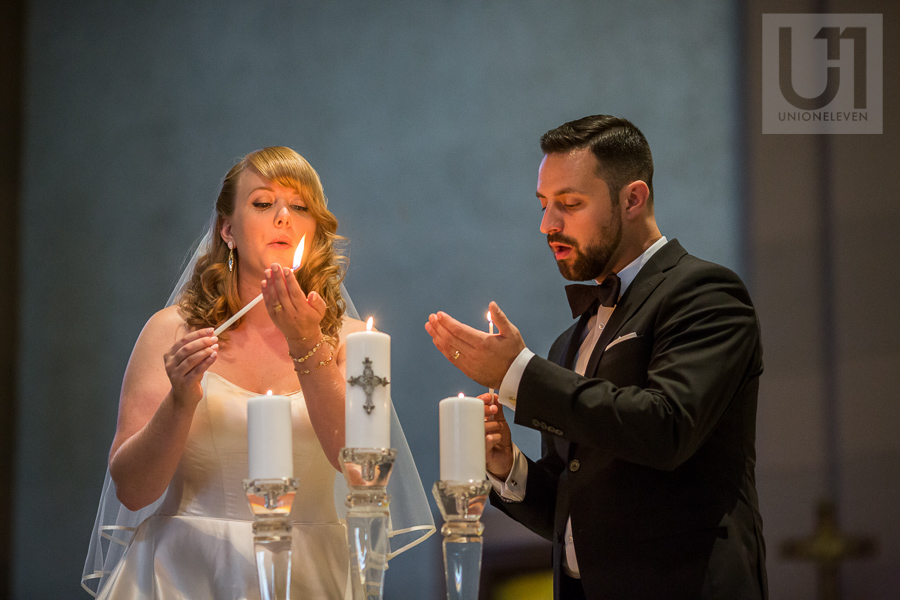 bride-and-groom-blowing-out-flame-after-lighting-candle-inside-ottawa-church-at-wedding