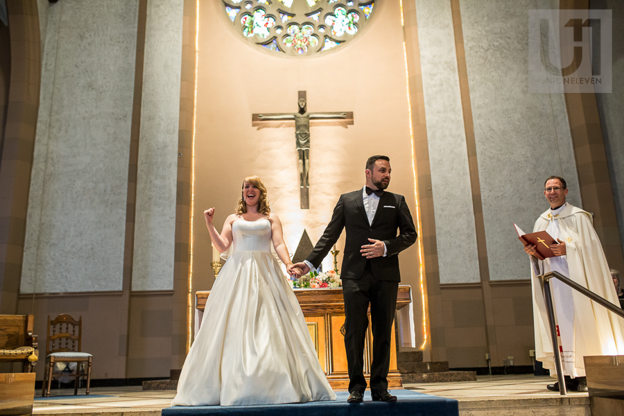 bride-fist-pumping-while-holding-grooms-hand-inside-church-after-ottawa-wedding-ceremony