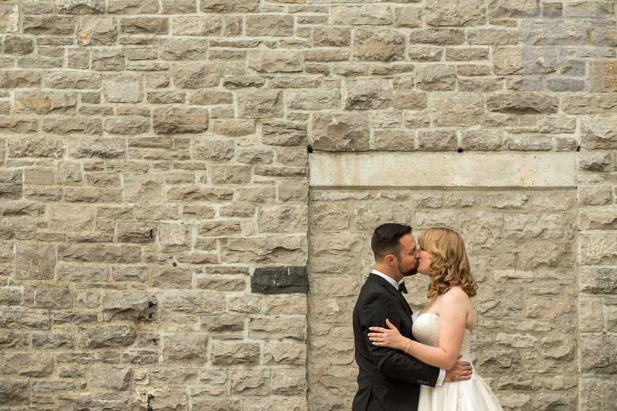 bride-and-groom-kissing-in-front-of-stone-wall-in-downtown-ottawa