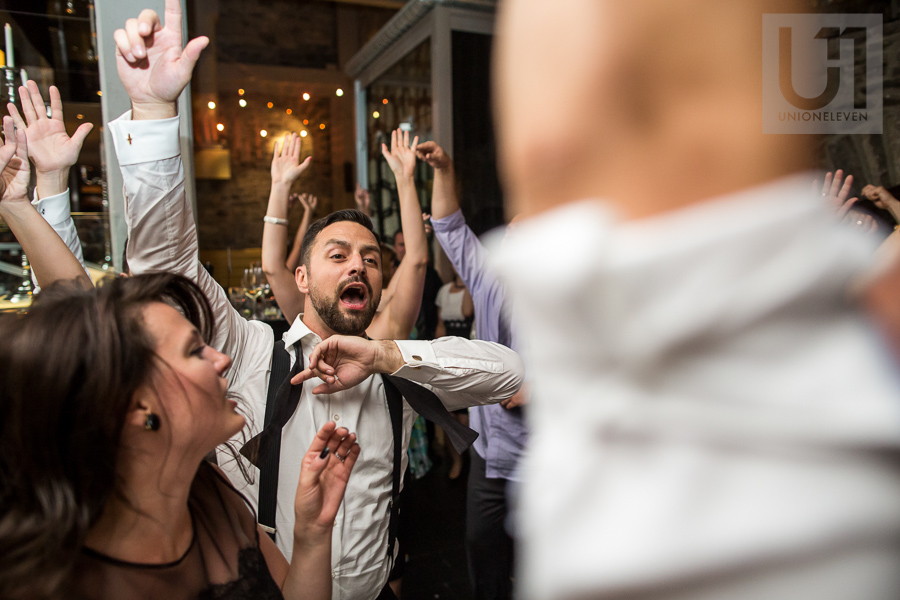 groom-dancing-with-hands-up-along-with-other-guests-during-wedding-reception-at-eighteen-restaurant-in-ottawa
