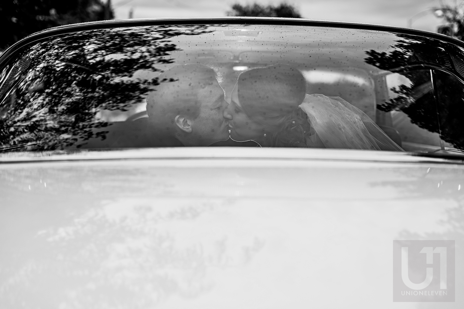 The bride and groom sharing a kiss on their car ride leaving the ceremony